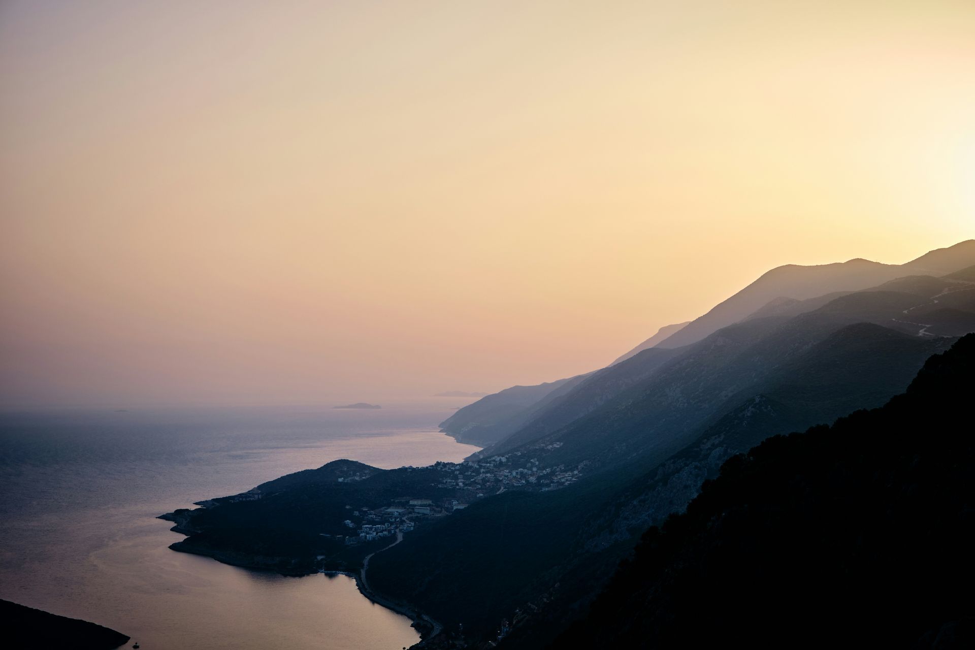 Coastal mountains at sunset, overlooking a town and the sea in Kaş, Turkey.