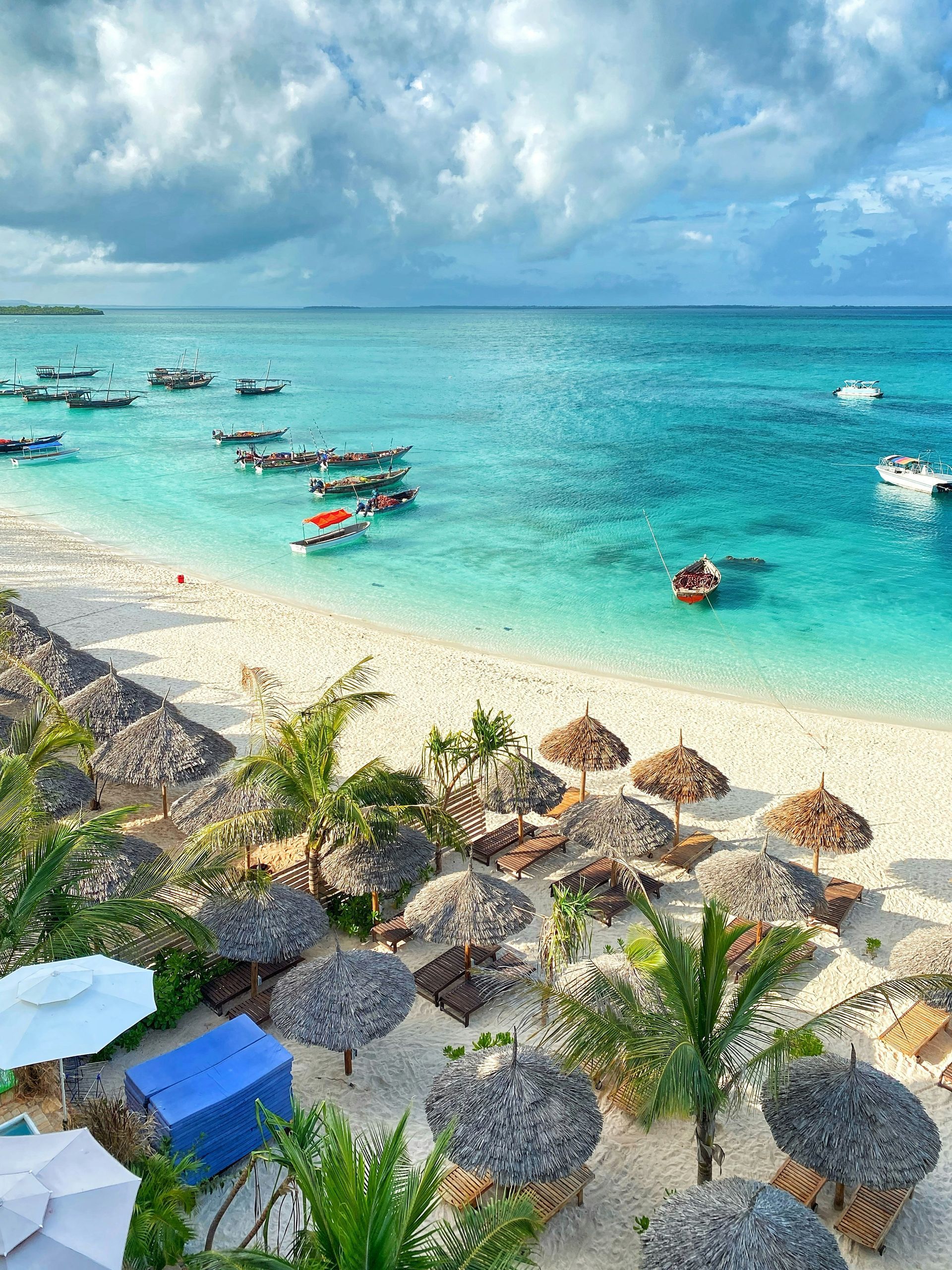 A beach with umbrellas and boats in the water in Zanzibar, Tanzania.
