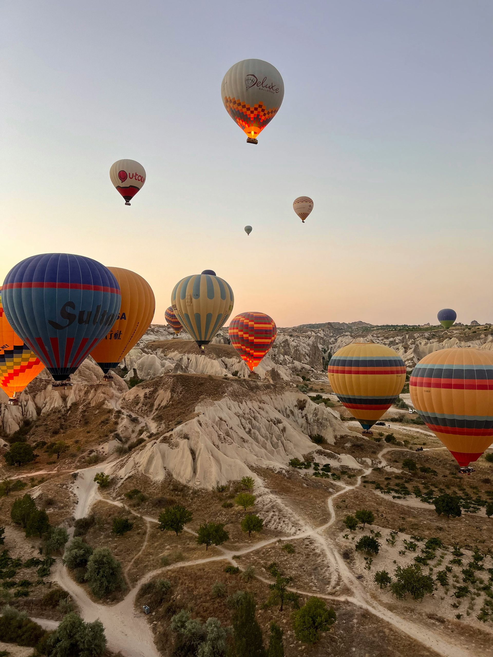 Hot air balloons ascend over Cappadocia, Turkey's unique rock formations at sunrise.