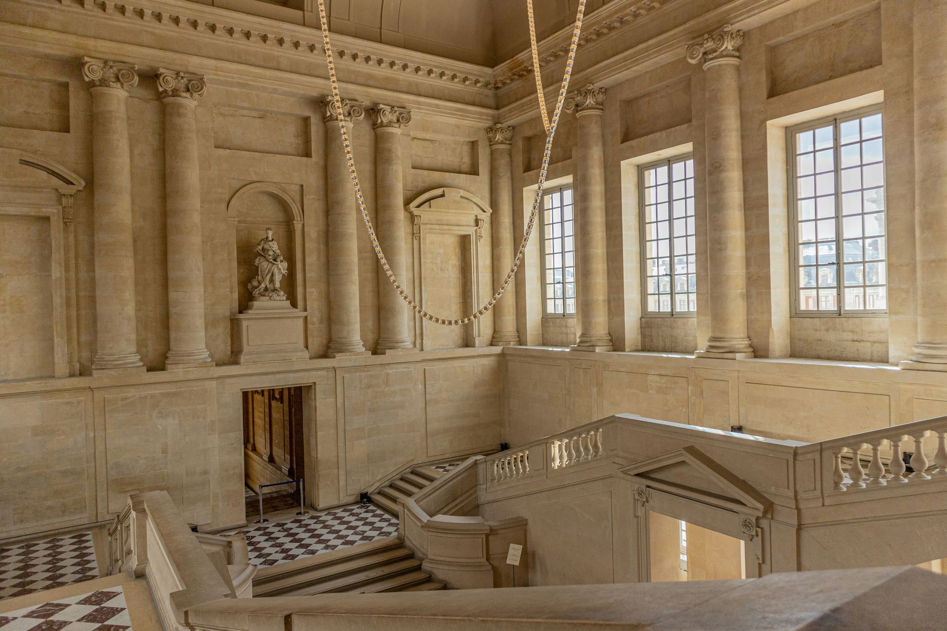 A staircase in a building with columns and windows at the Palace of Versailles in France.