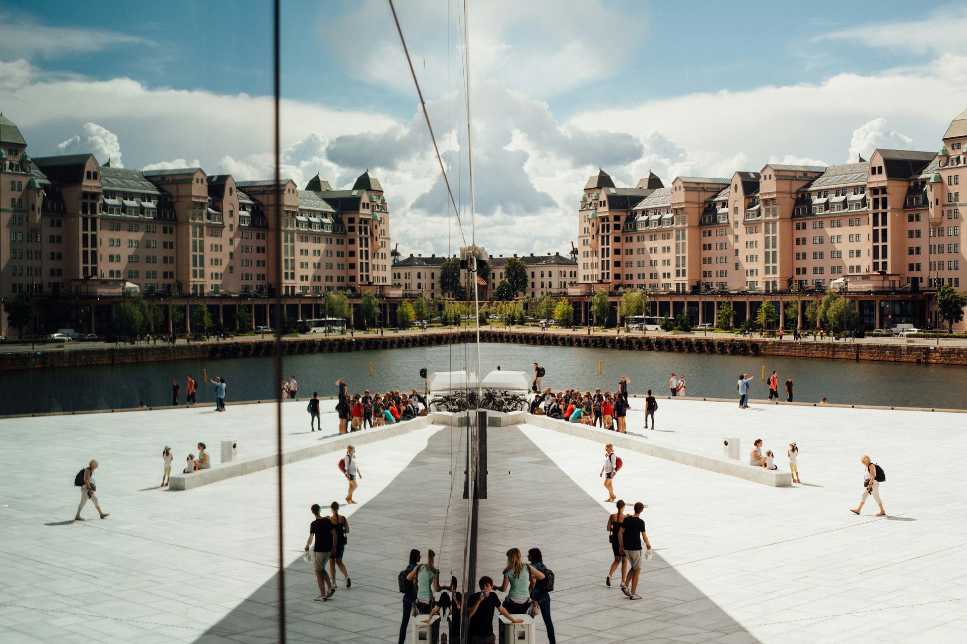 Reflection of waterfront buildings and people on mirrored wall, Oslo.