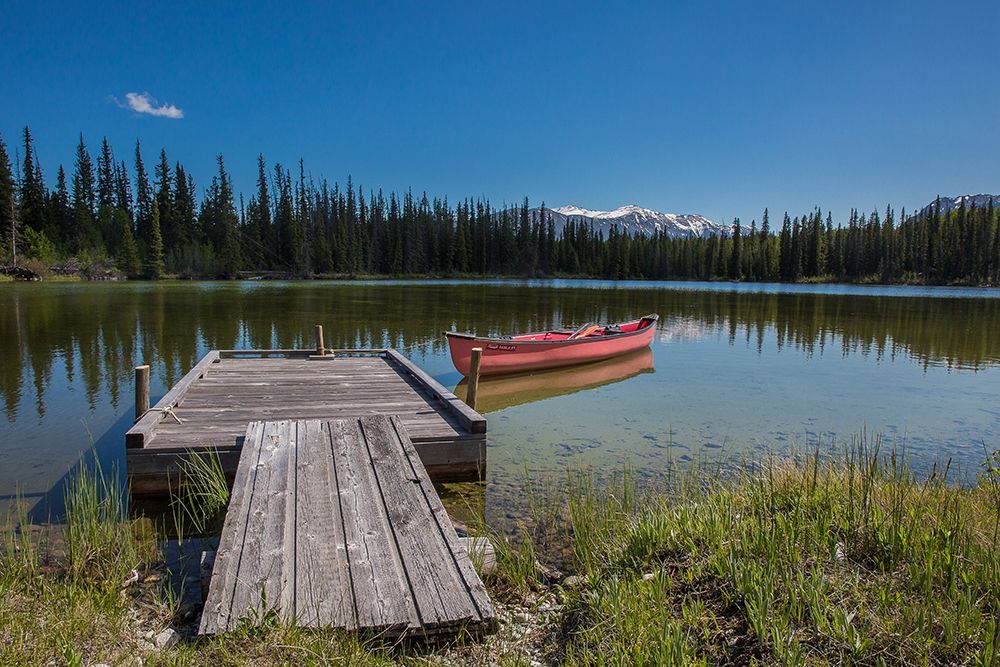 A red canoe is docked at a wooden dock on Chilko Lake, Canada.