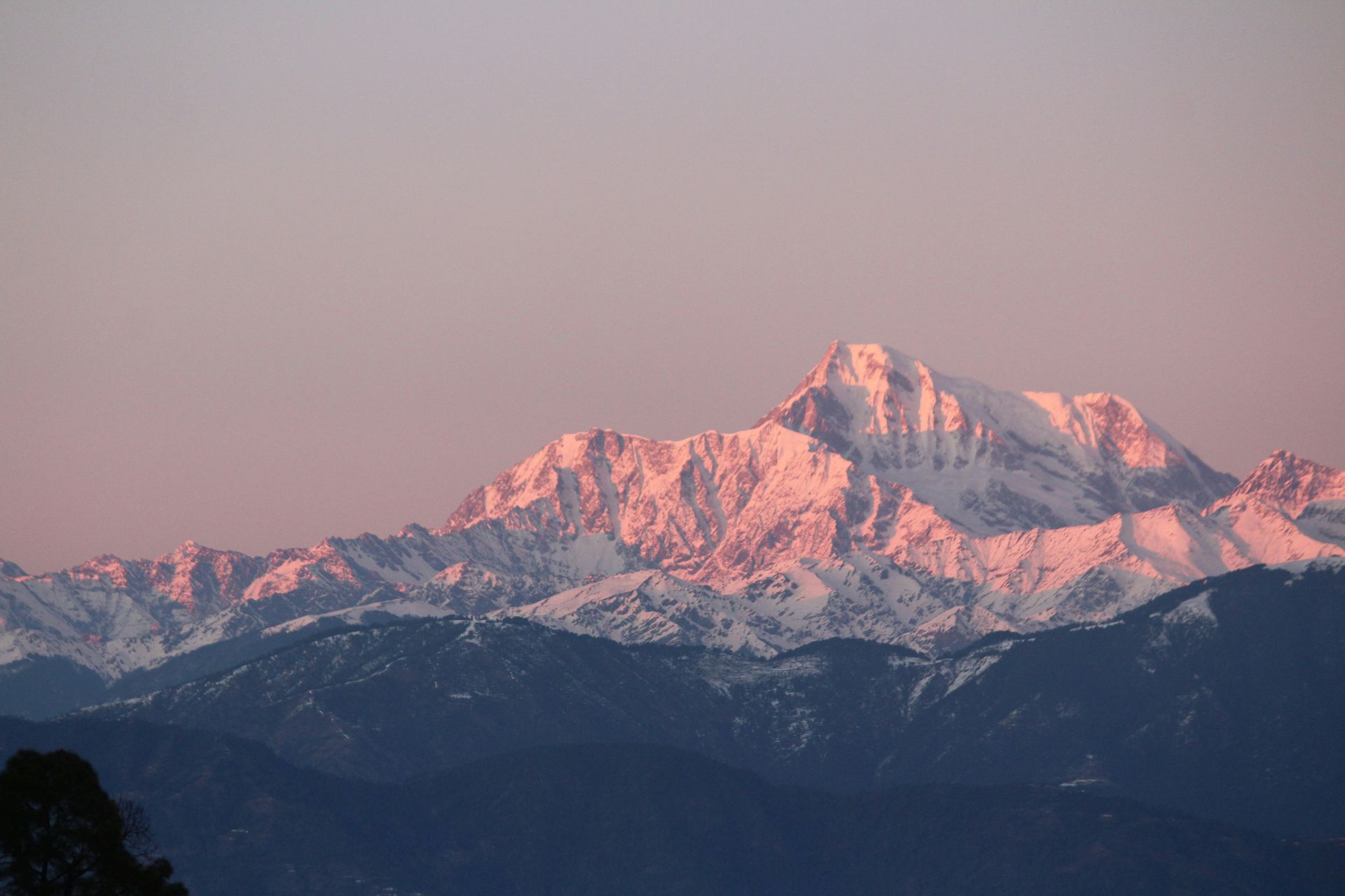Snow-capped mountain range of Mount Everest at sunrise, with pink-tinged peaks in Nepal.