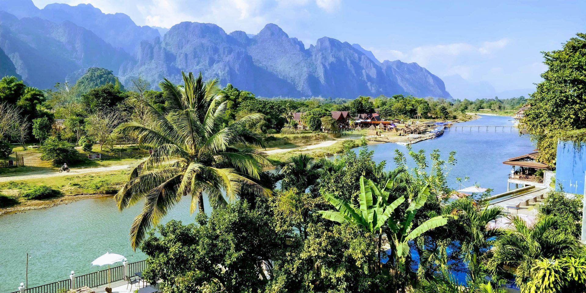 Scenic view of a river winding through lush green landscape with mountains in the background in Vang Vieng, Laos.