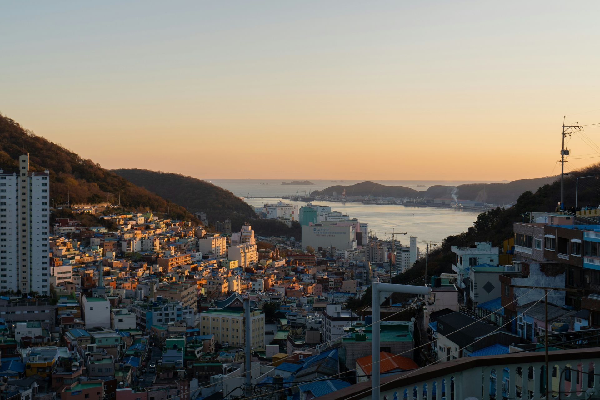 Busan at sunset with buildings and a bridge over water in South Korea.