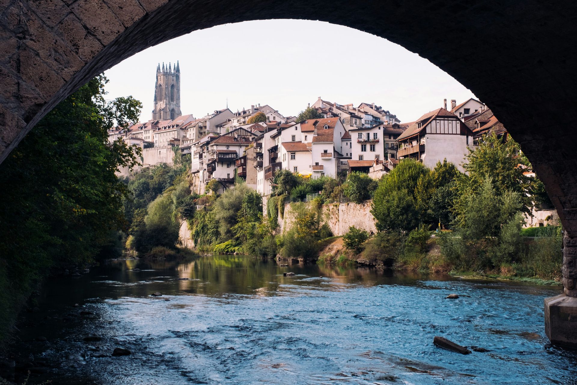 A view of a historic town of Freiburg nestled beside a river, framed by an archway in Germany.