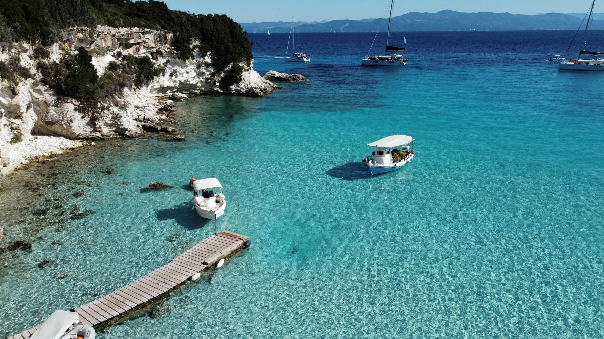 There are many boats in the water and a dock in the foreground in Corfu, Greece.