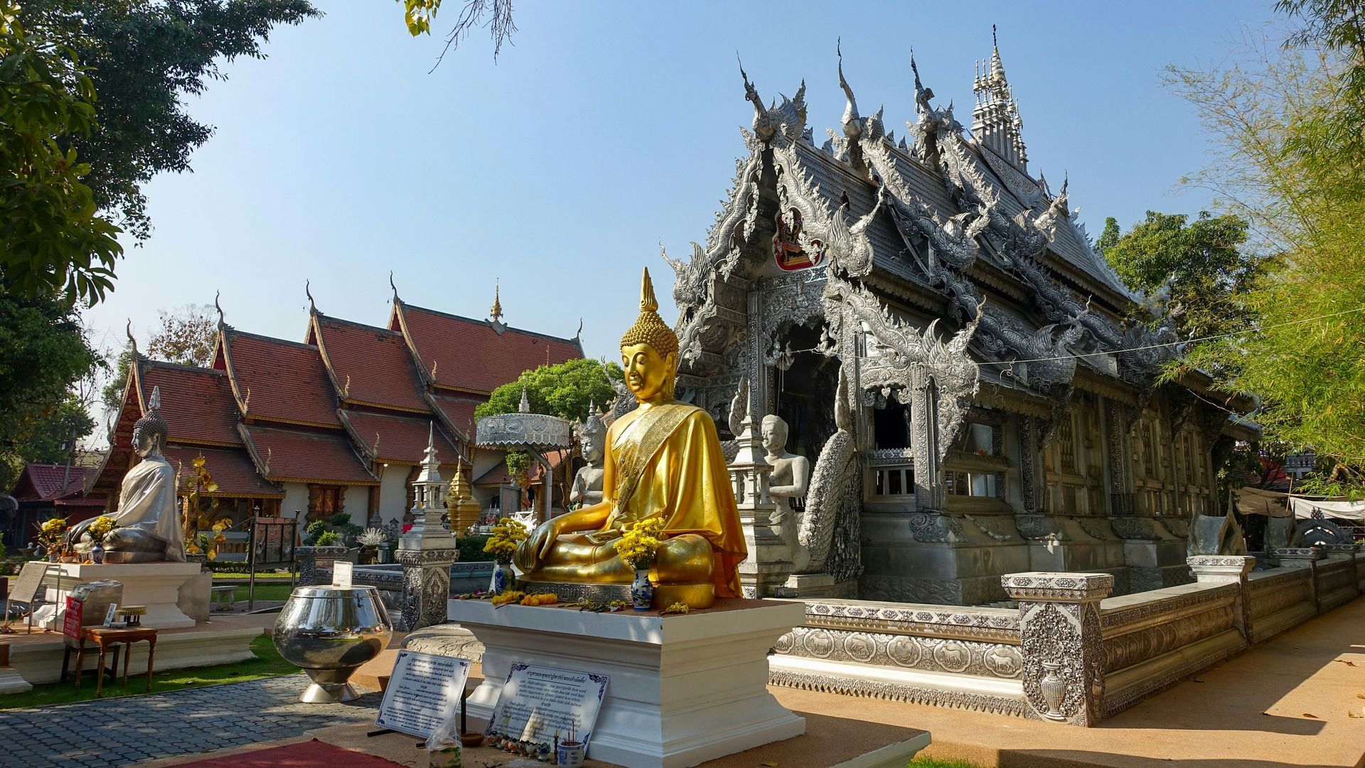 A golden Buddha statue is sitting in front of a temple in Chiang Mai, Thailand.