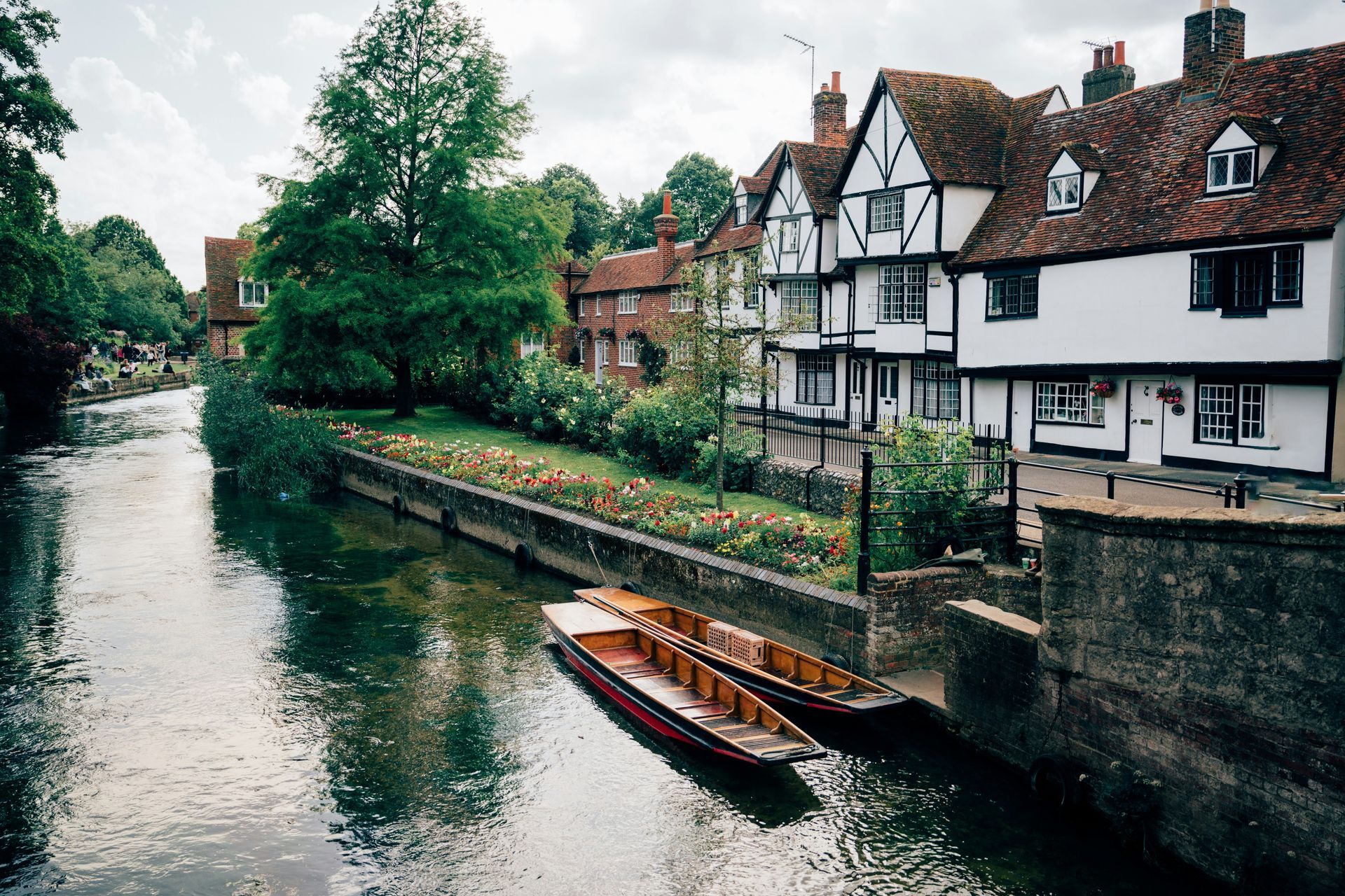 Boats docked on a river in front of half-timbered buildings in Canterbury, England.