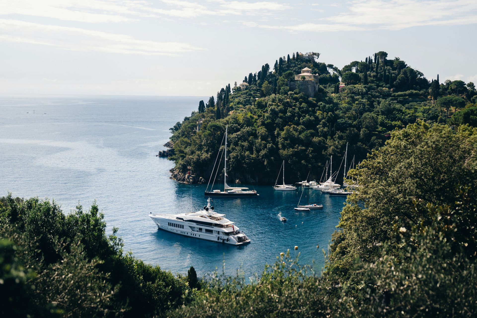 A large yacht is floating on top of a body of water surrounded by trees in Portofino, Italy.