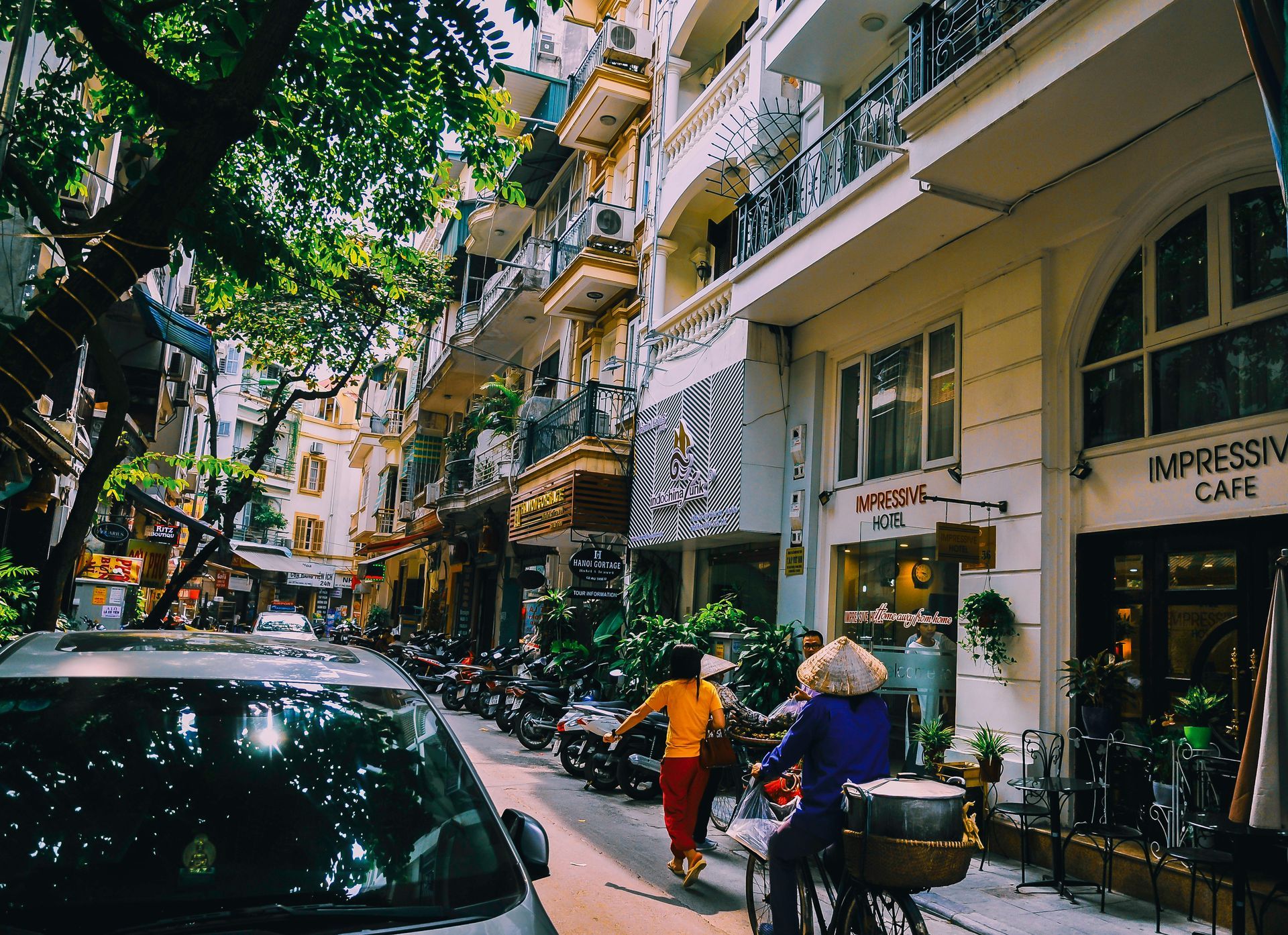 A woman is riding a bicycle down a narrow street in Vietnam.