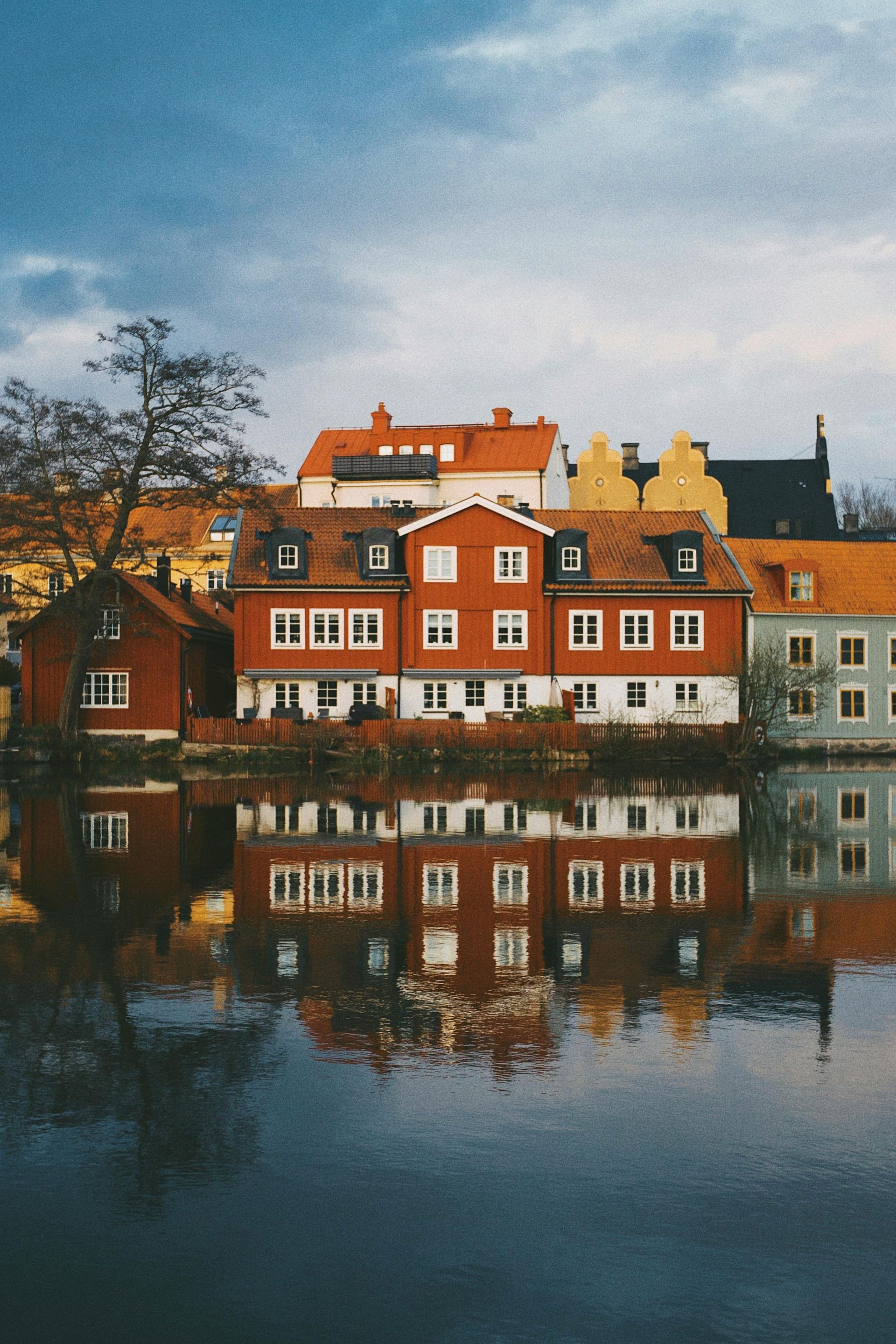 A group of buildings are reflected in a body of water in Sweden.