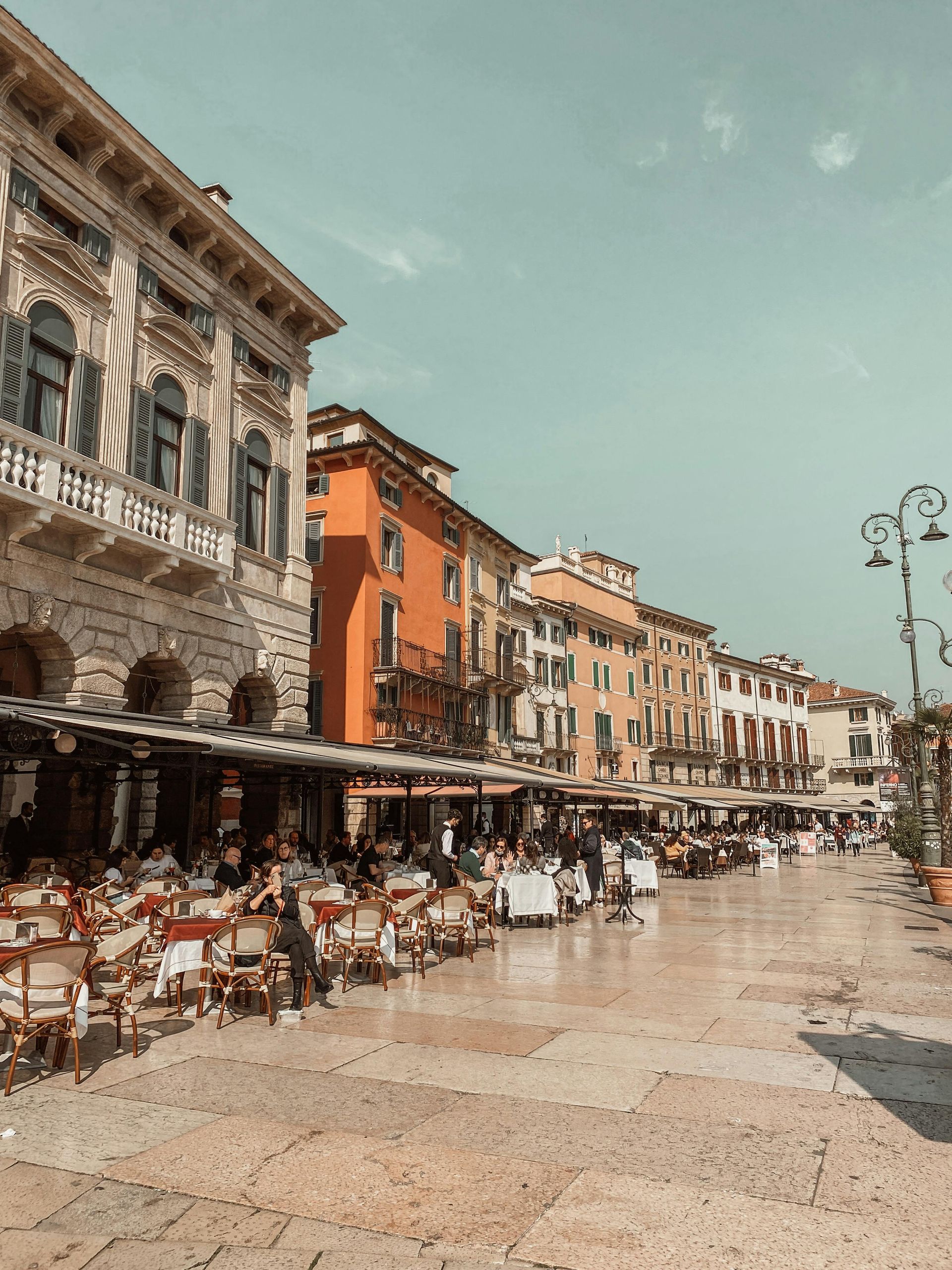 A row of buildings with tables and chairs in front of them in Verona, Italy.