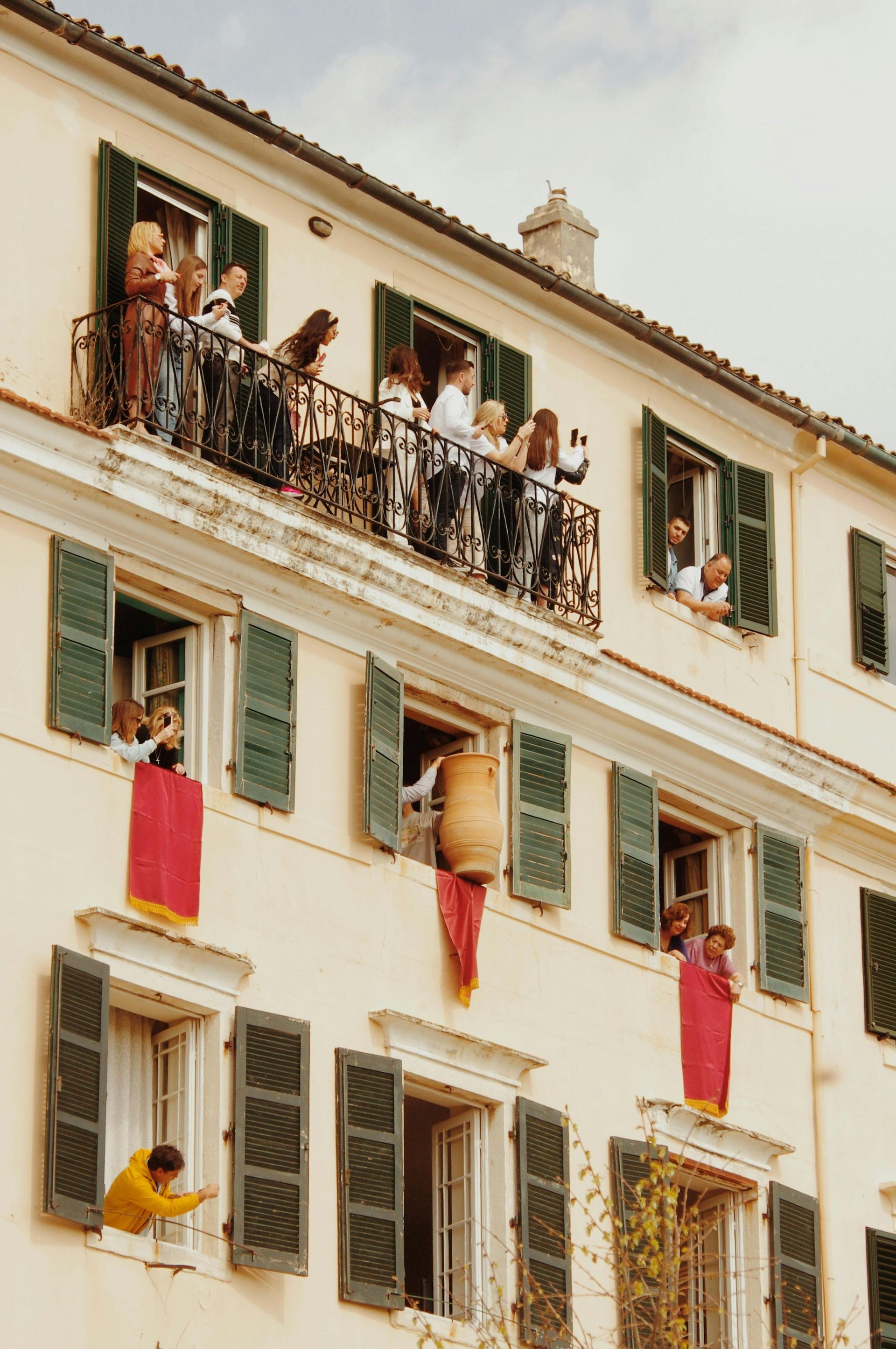 A group of people are looking out of the windows of a building in Corfu, Greece.