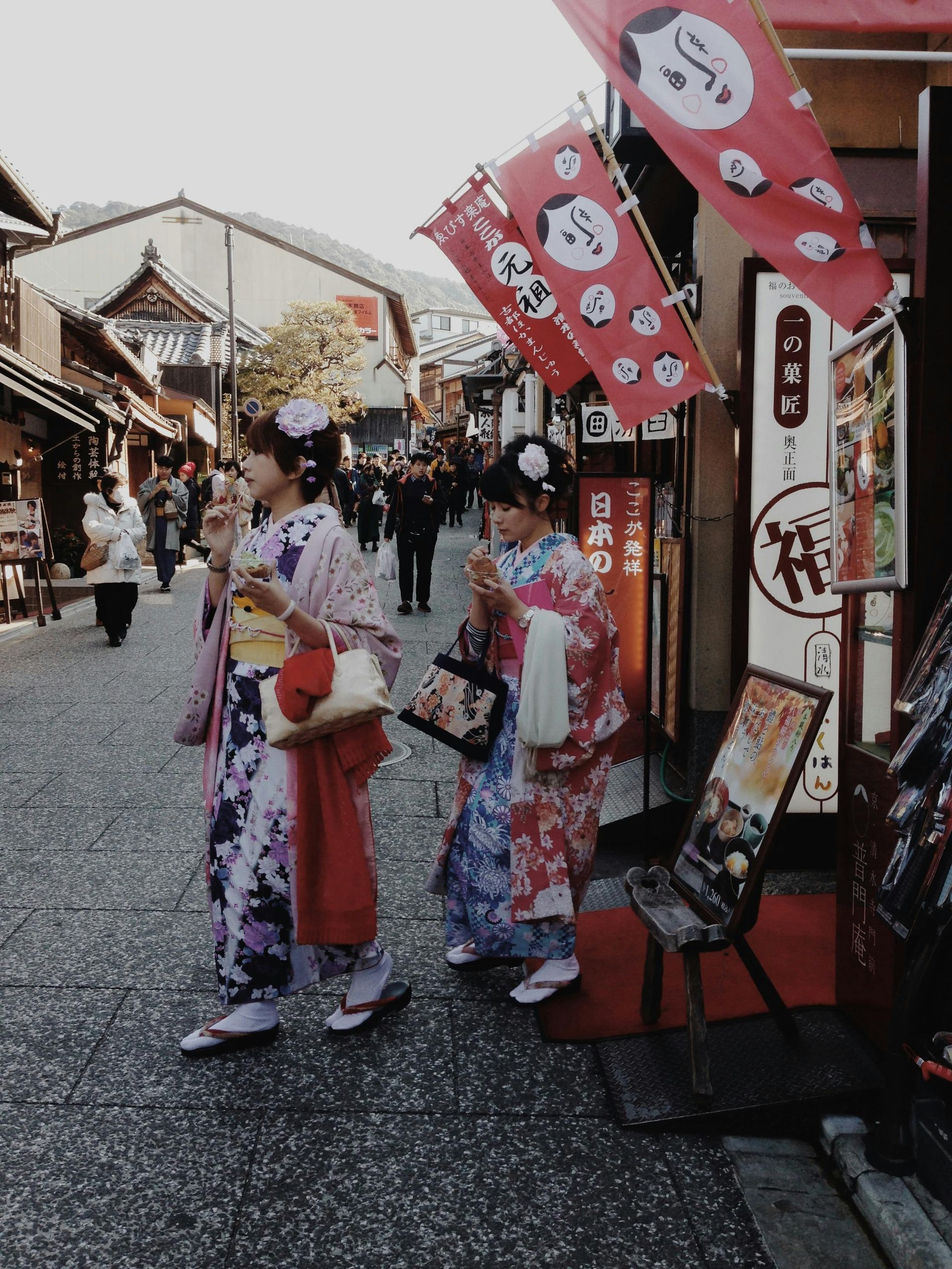 Three women in kimonos are walking down a street on Japanese Street. 