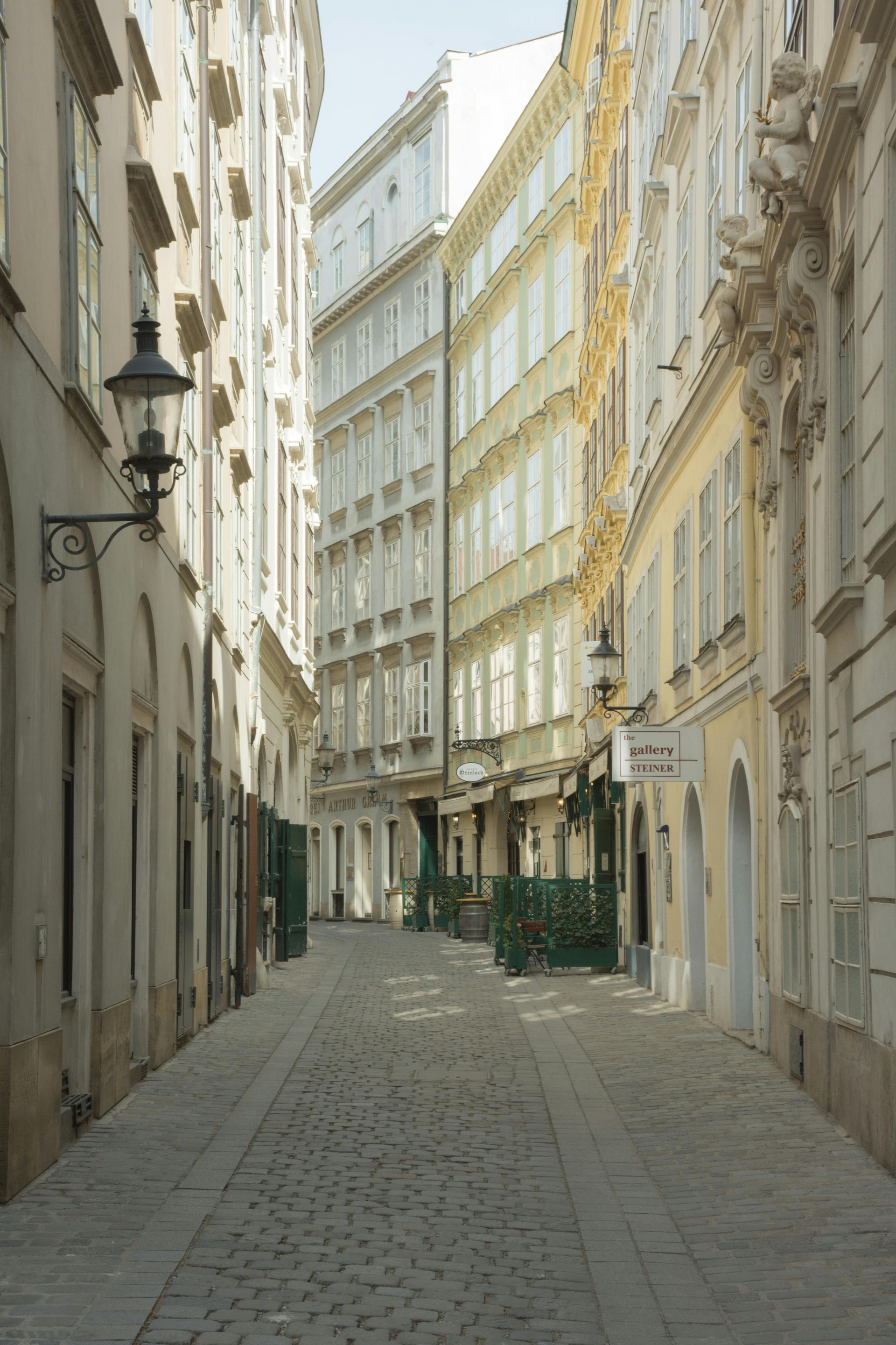 A narrow cobblestone street between two tall buildings in old town Vienna, Austria. 