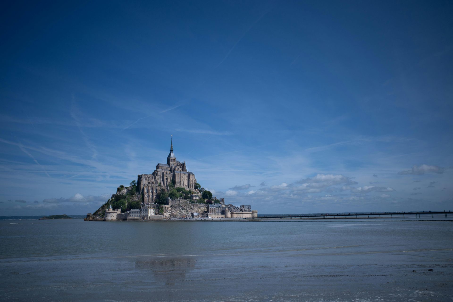 A small island in the middle of the ocean with a castle on top of it called Mont Saint-Michel in Normandy, France.