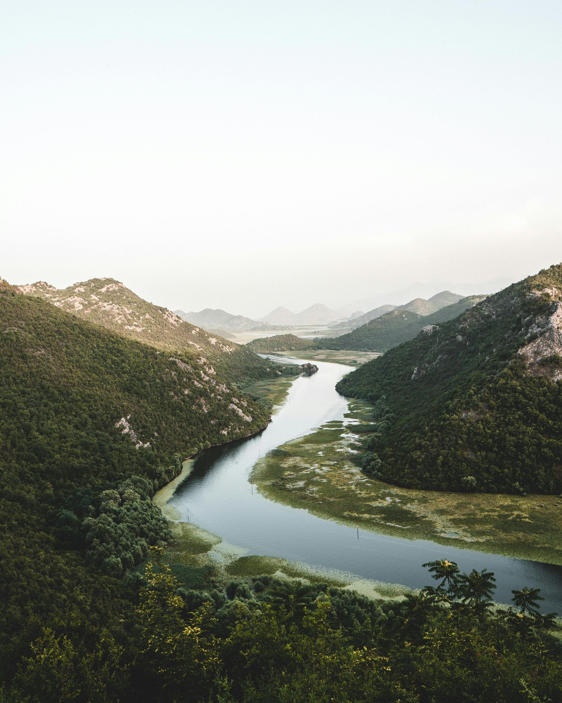 Shkodra Lake runs through a valley surrounded by mountains in the Balkans.