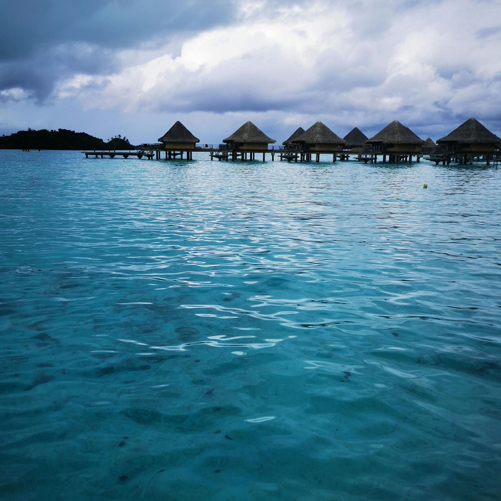 A row of huts on stilts in the middle of the ocean in French Polynesia.