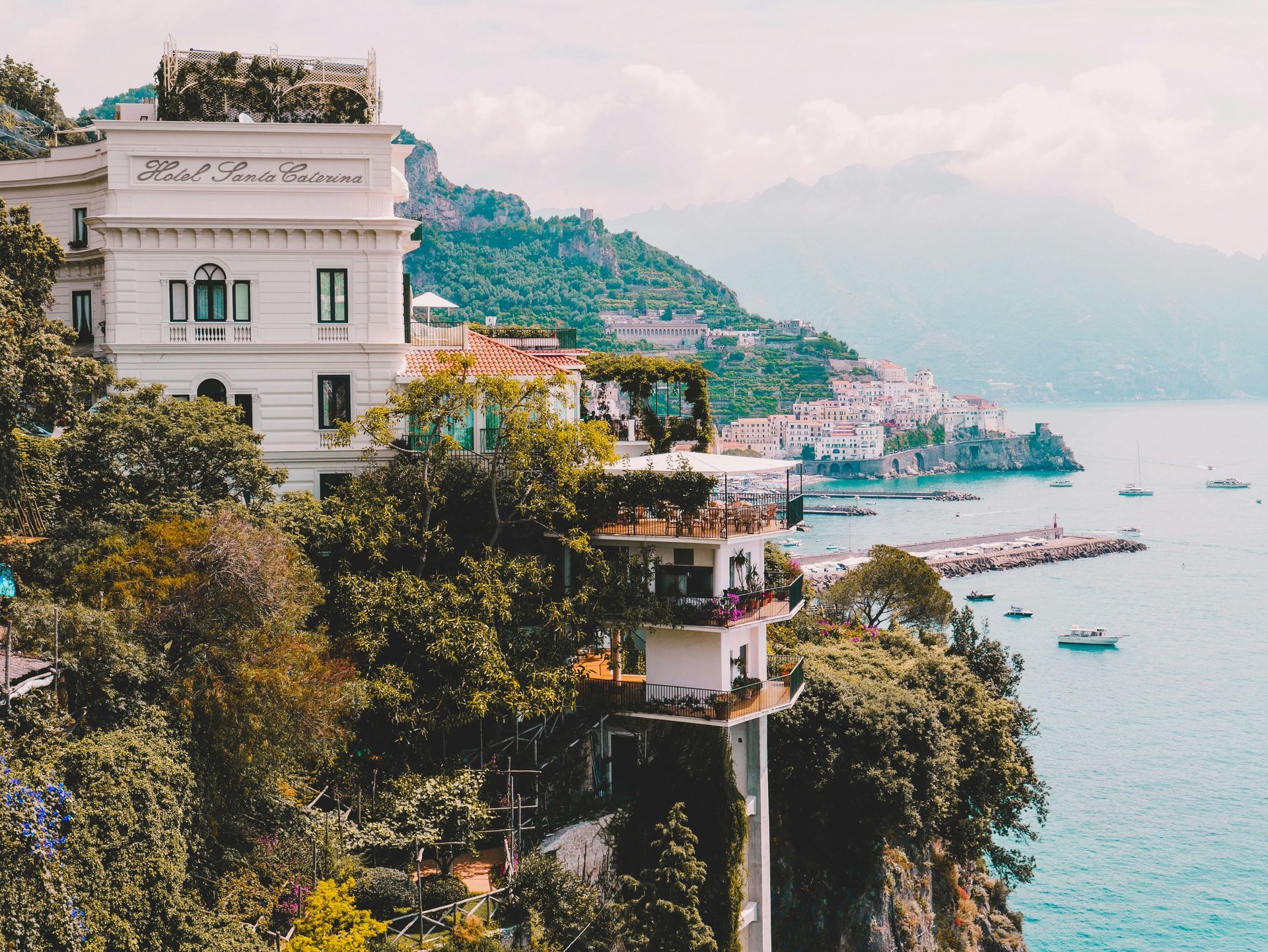 A large white building is sitting on top of a cliff overlooking the ocean in the Amalfi Coast, Italy.