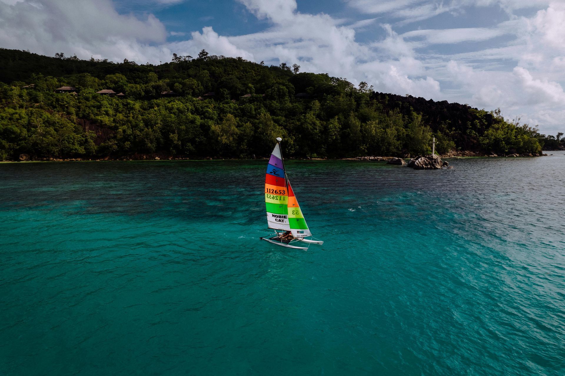 A person is sailing a sailboat in the ocean on Seychelles Island.