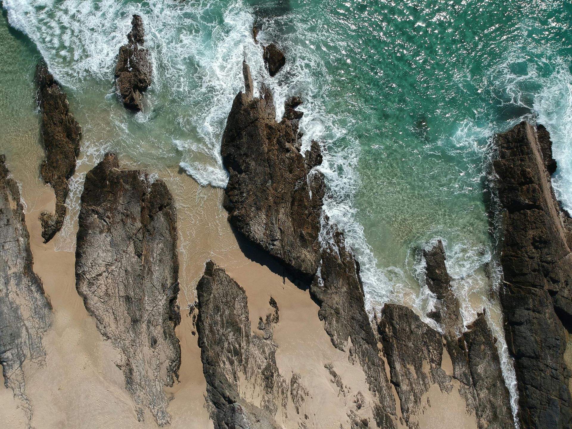 An aerial view of a beach with rocks and waves in Australia.