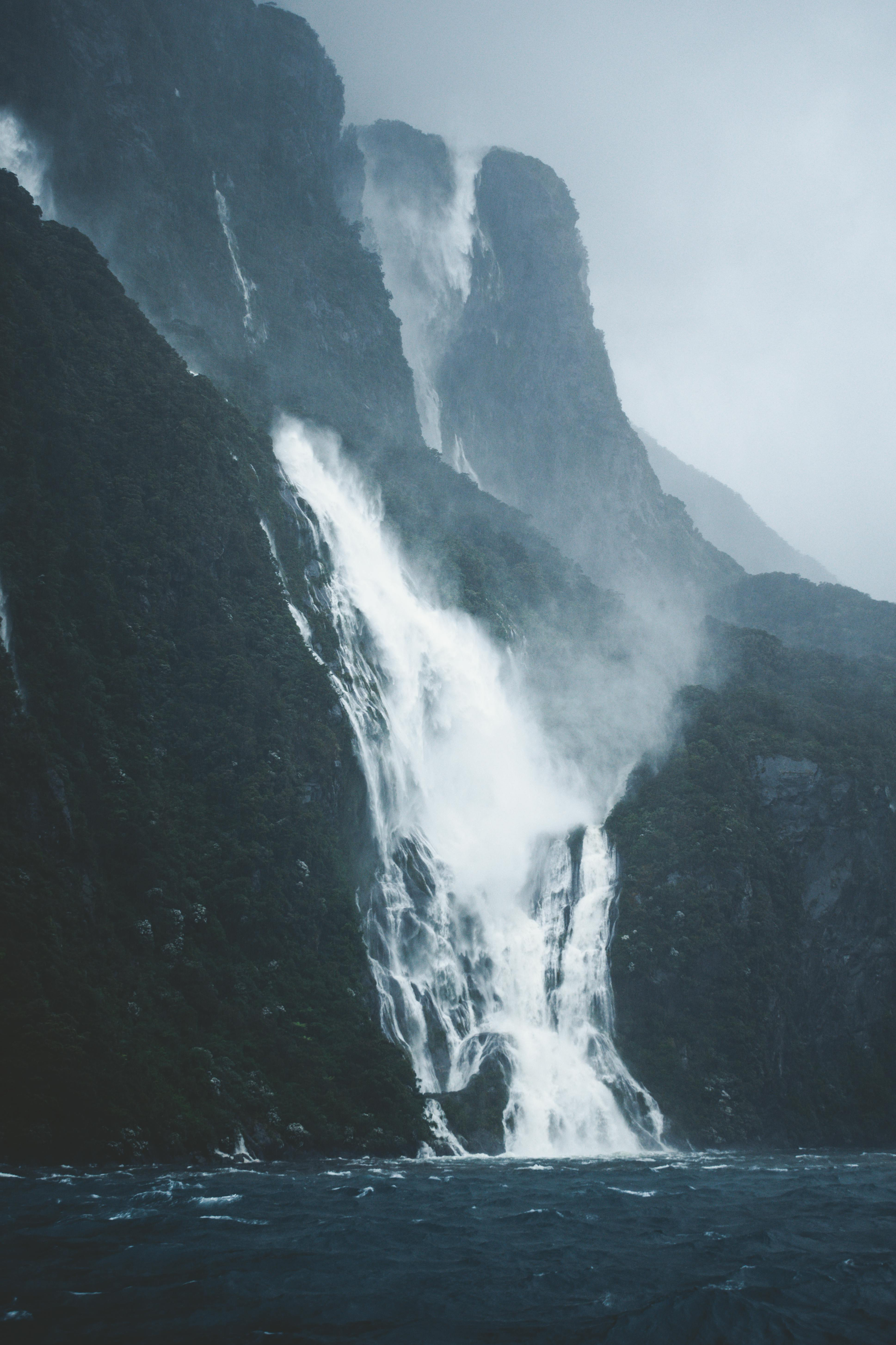 A waterfall is coming down a mountain into the ocean in New Zeland.