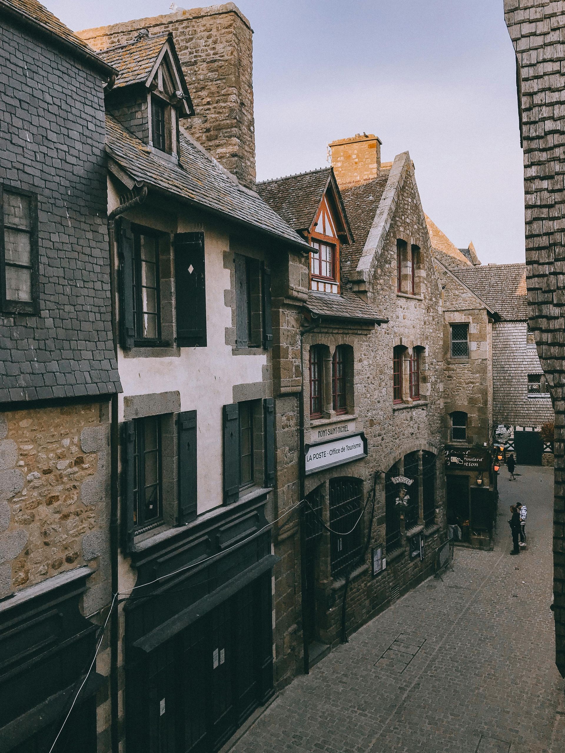 An aerial view of a narrow street lined with brick buildings in Normandy, France.