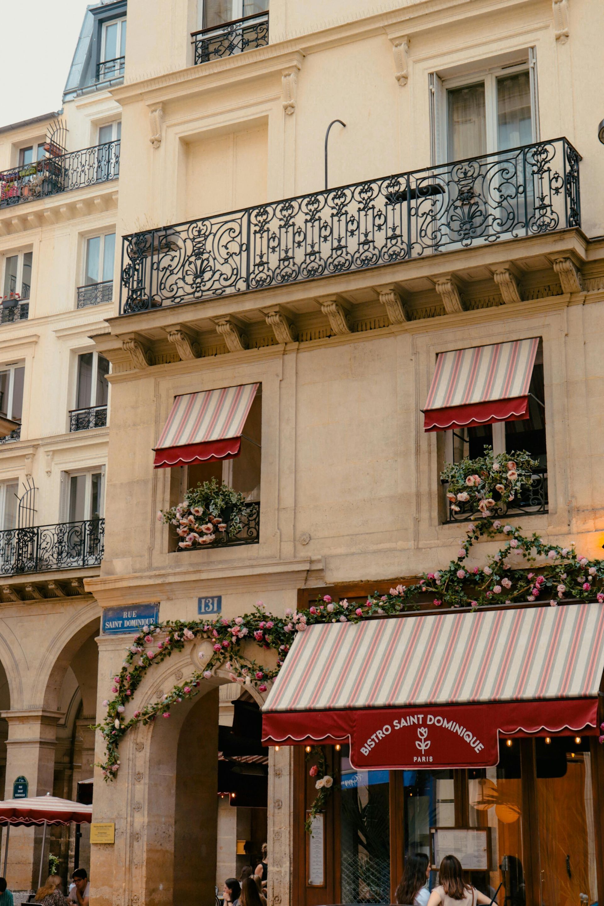 A building with a red and white awning on the front of it on a street in Paris.