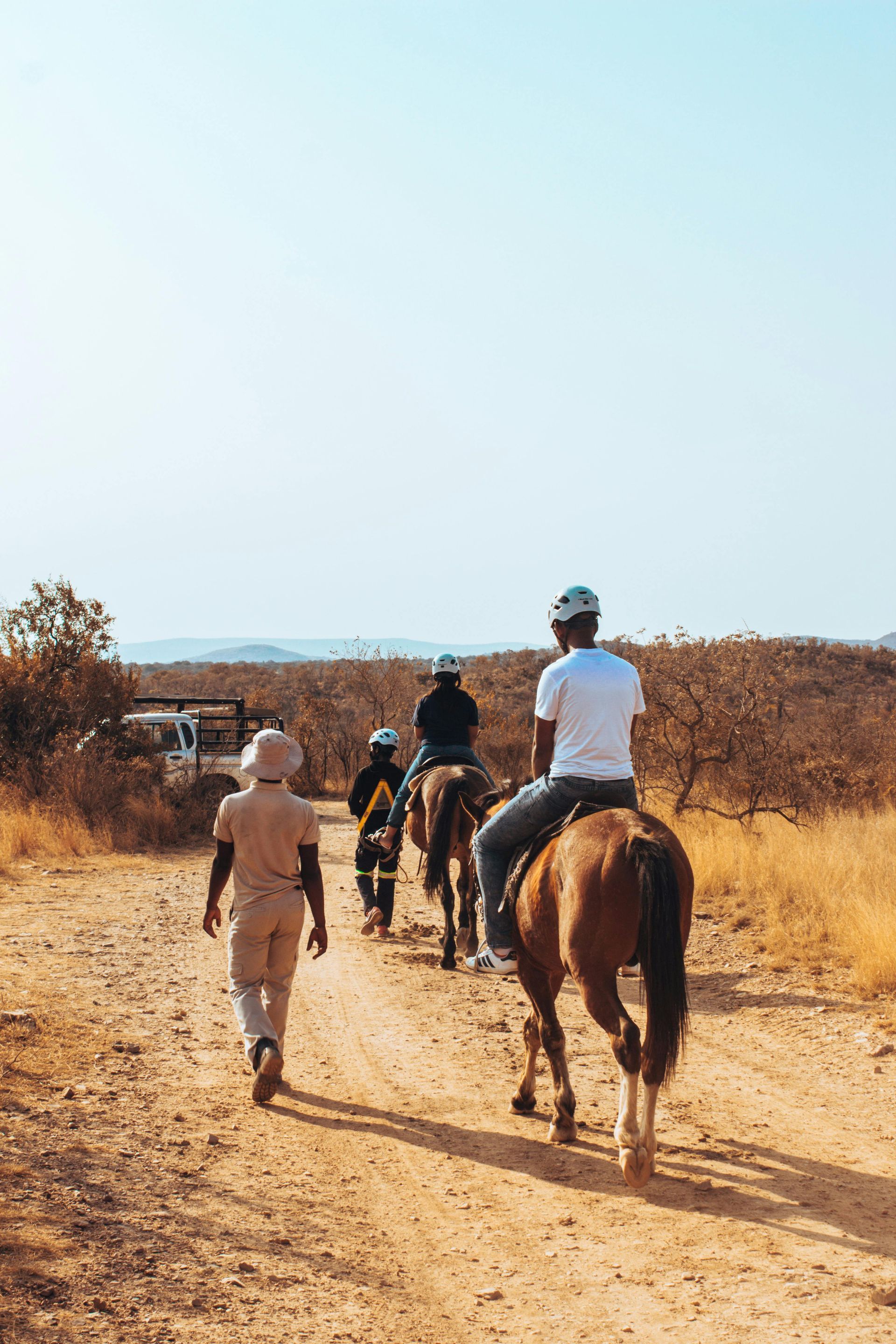 A group of people riding horses down a dirt road in Botswana, Africa.