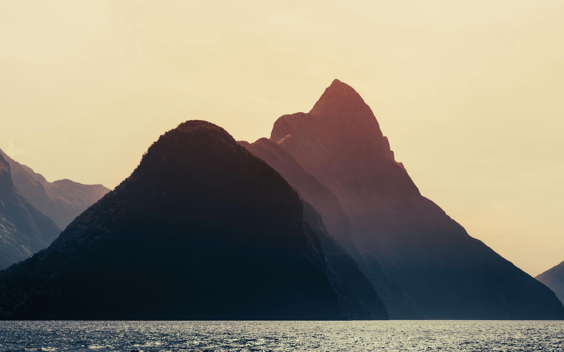 A couple of mountains sitting on top of a body of water in New Zealand. 