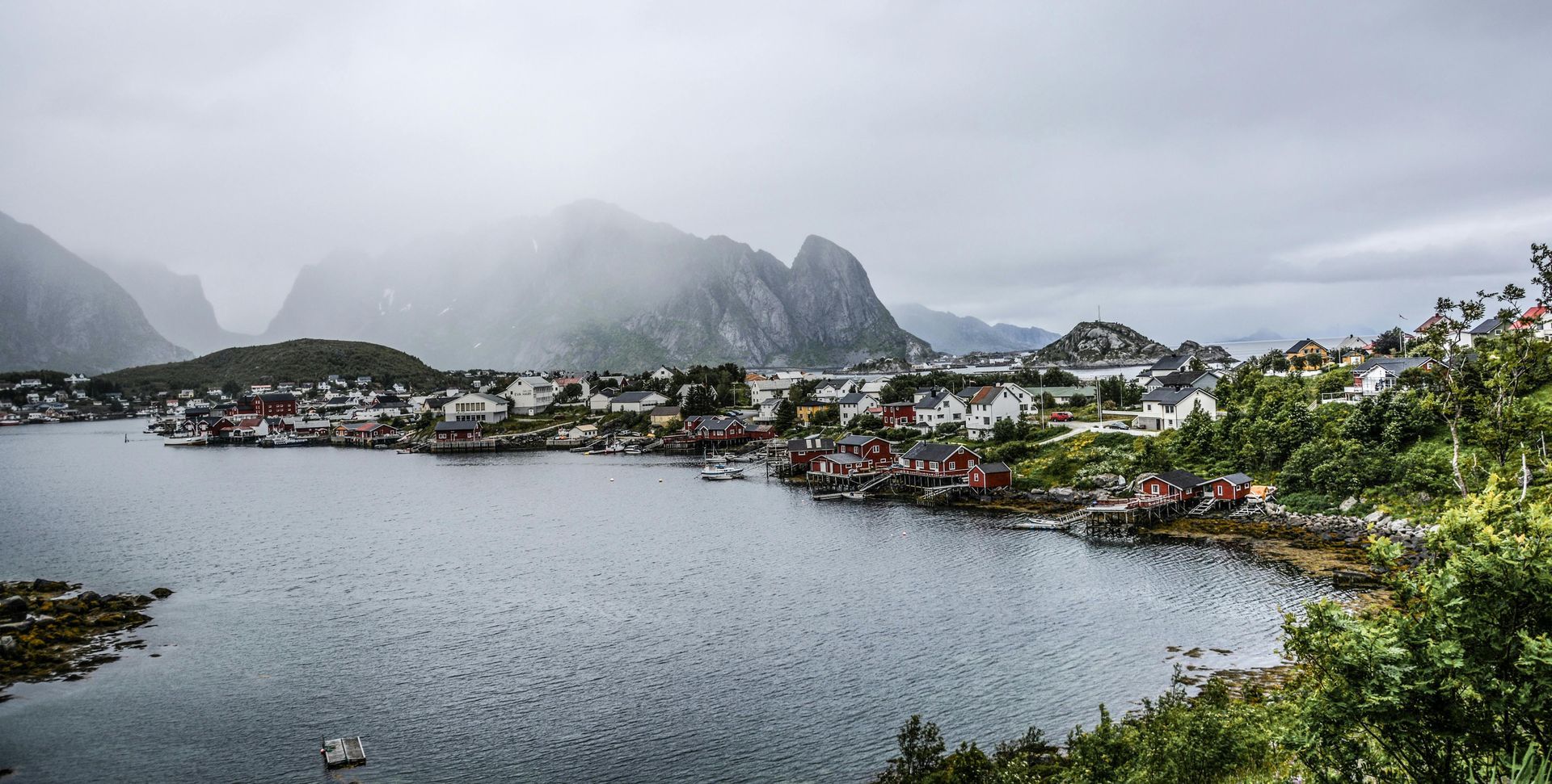 A small town sits on the shore of a lake surrounded by mountains in Norway.