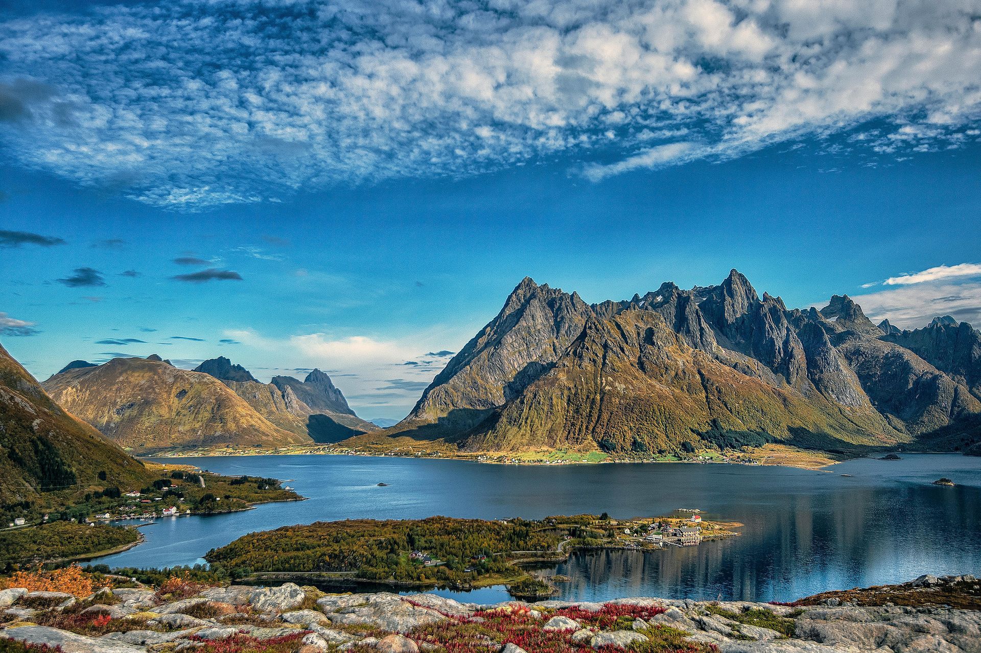 A lake with mountains in the background and a blue sky on the Norwegian Coast.