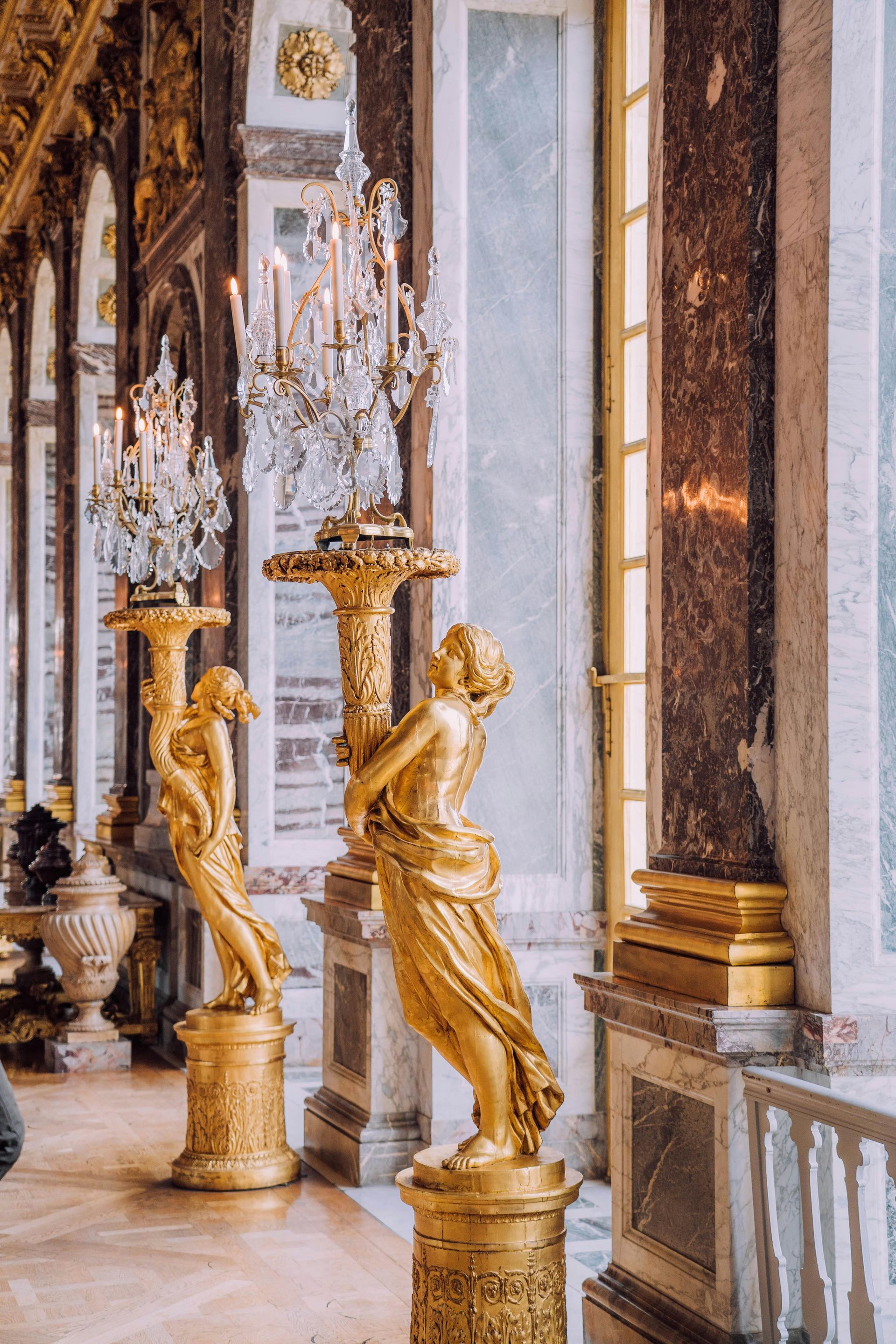 A room with a lot of statues and chandeliers in it in northern France. 