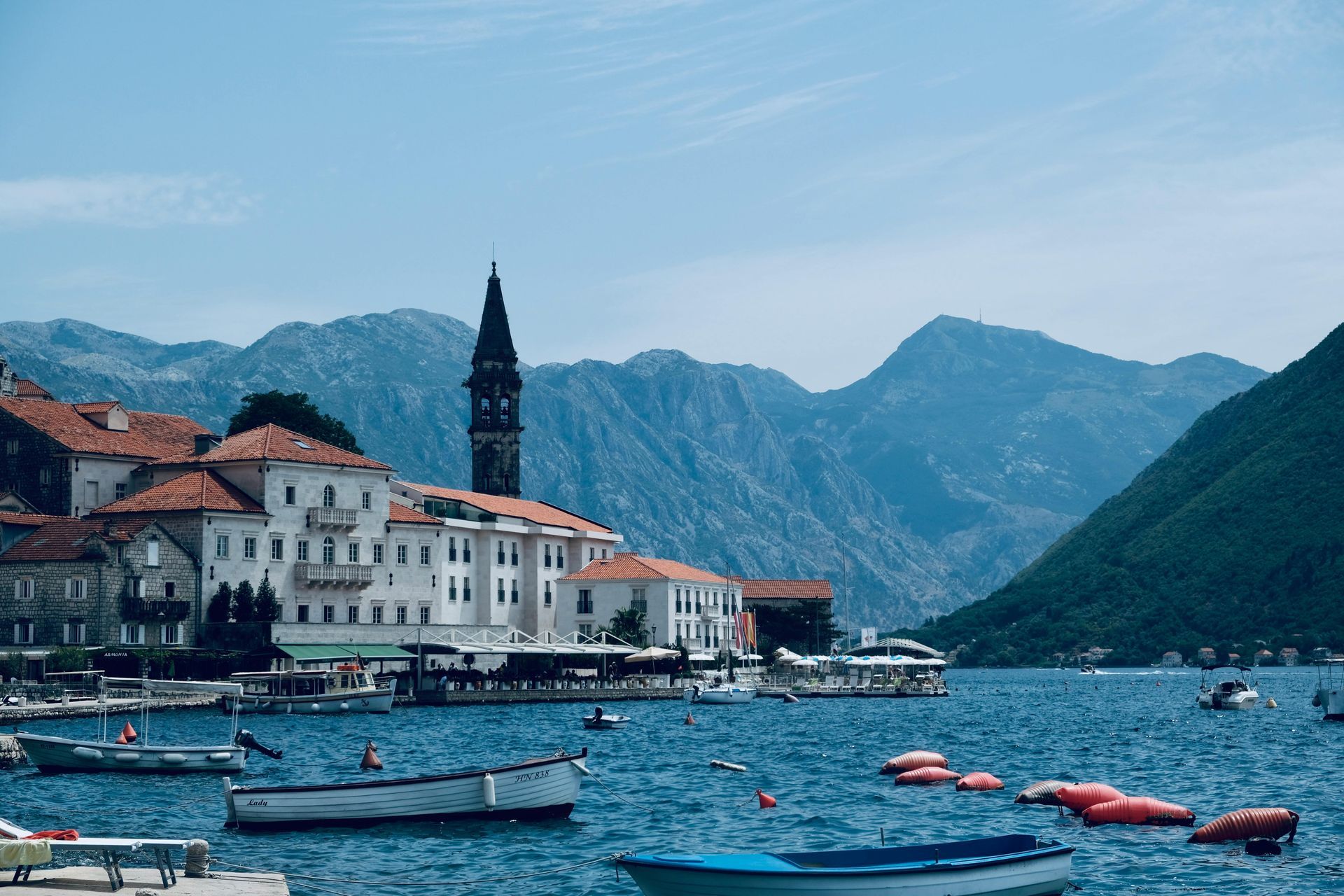 There are many boats in the Bay of Kotor, with mountains in the background of Montenegro. 