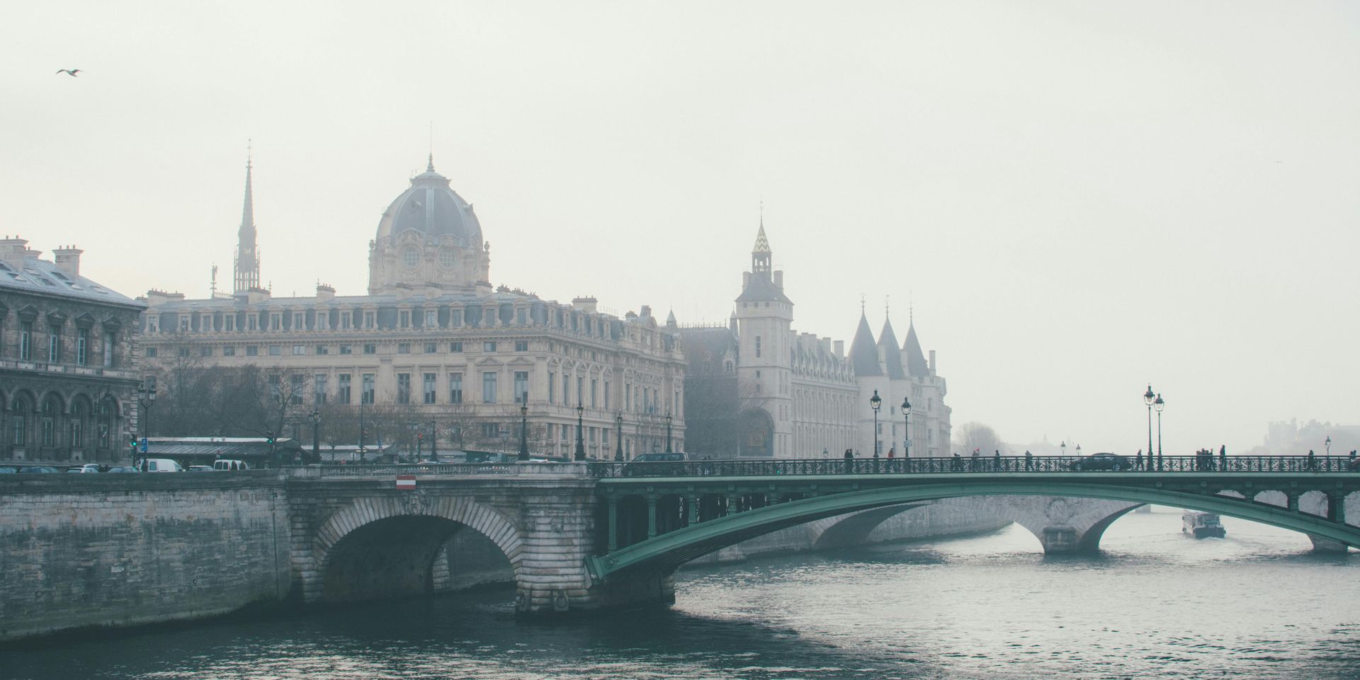 A bridge over a river with a building in the background in Paris.