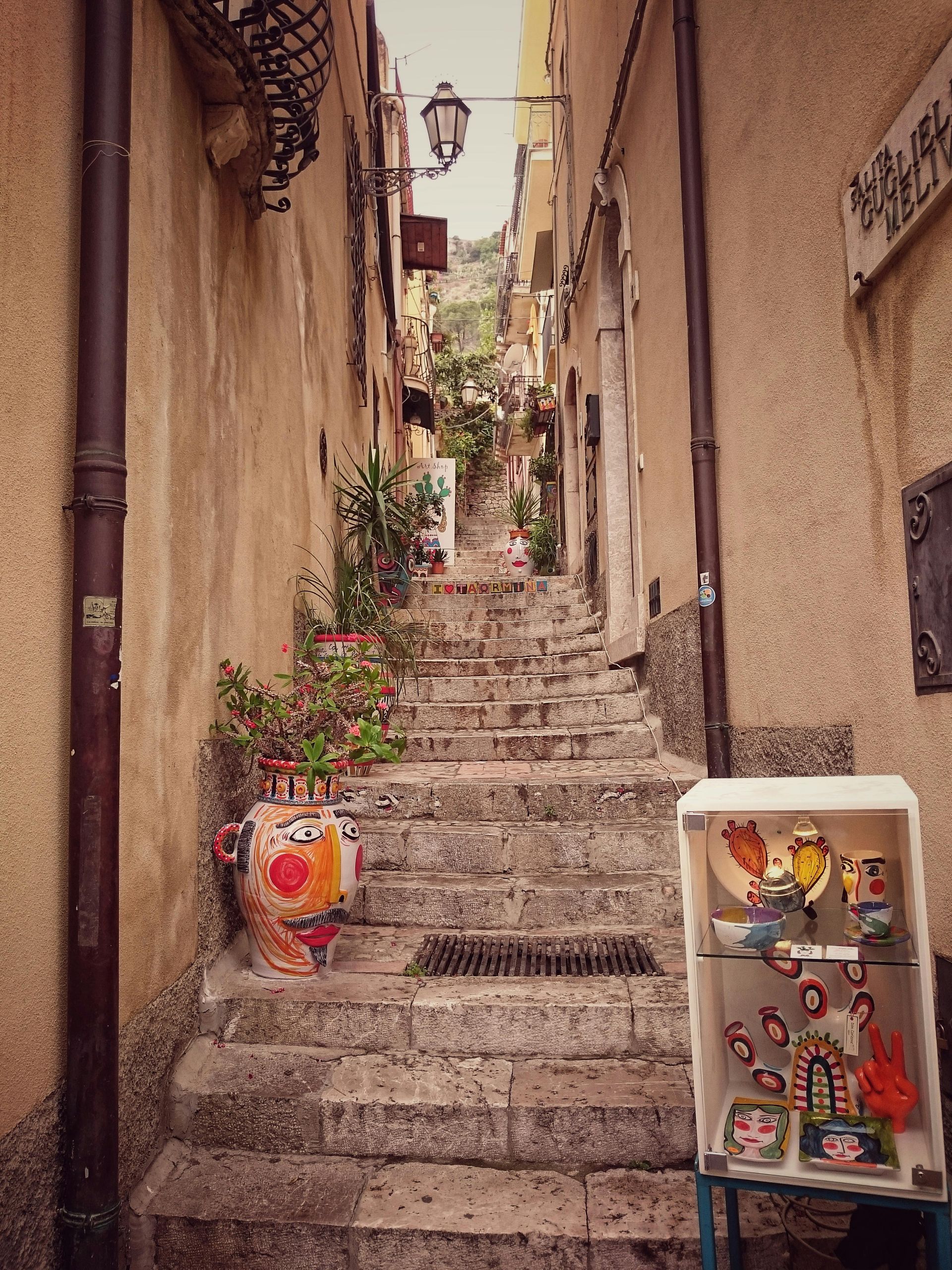 A narrow alleyway with stairs leading up to a store in Sicily, Italy.