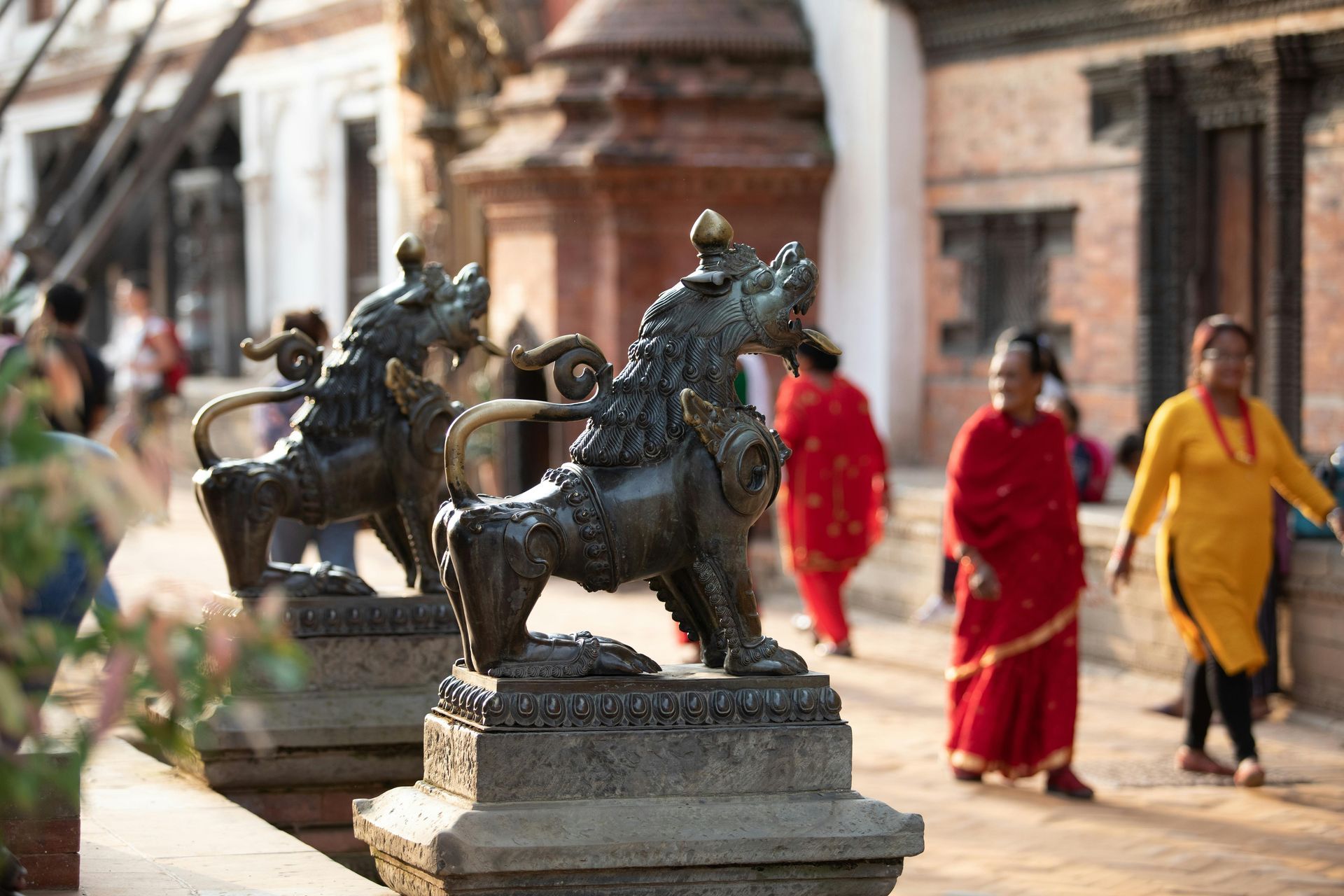 A group of people are walking in front of a statue of a lion in Bhutan.