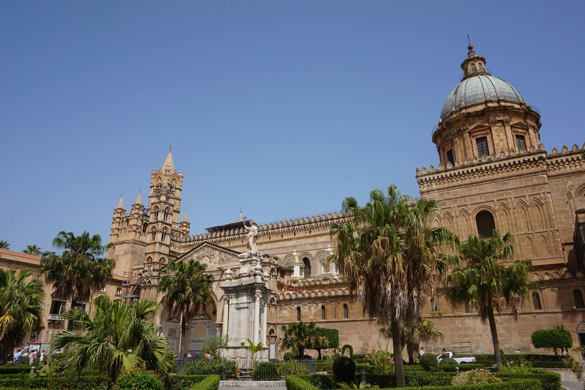 A large building with a dome and palm trees in front of it in Sicily, Italy.