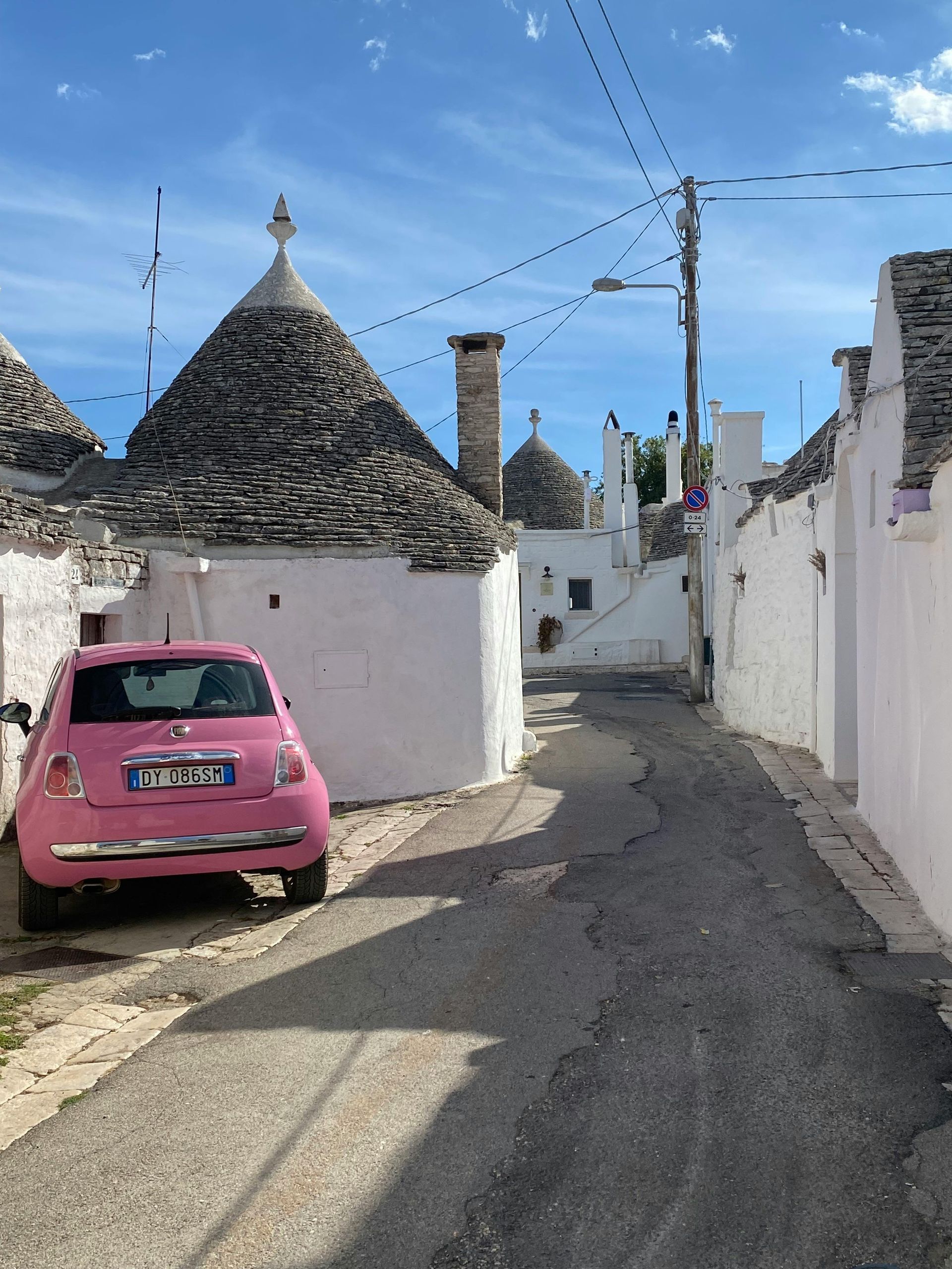 A pink car is parked on the streets of Alberobello in Puglia, Italy.