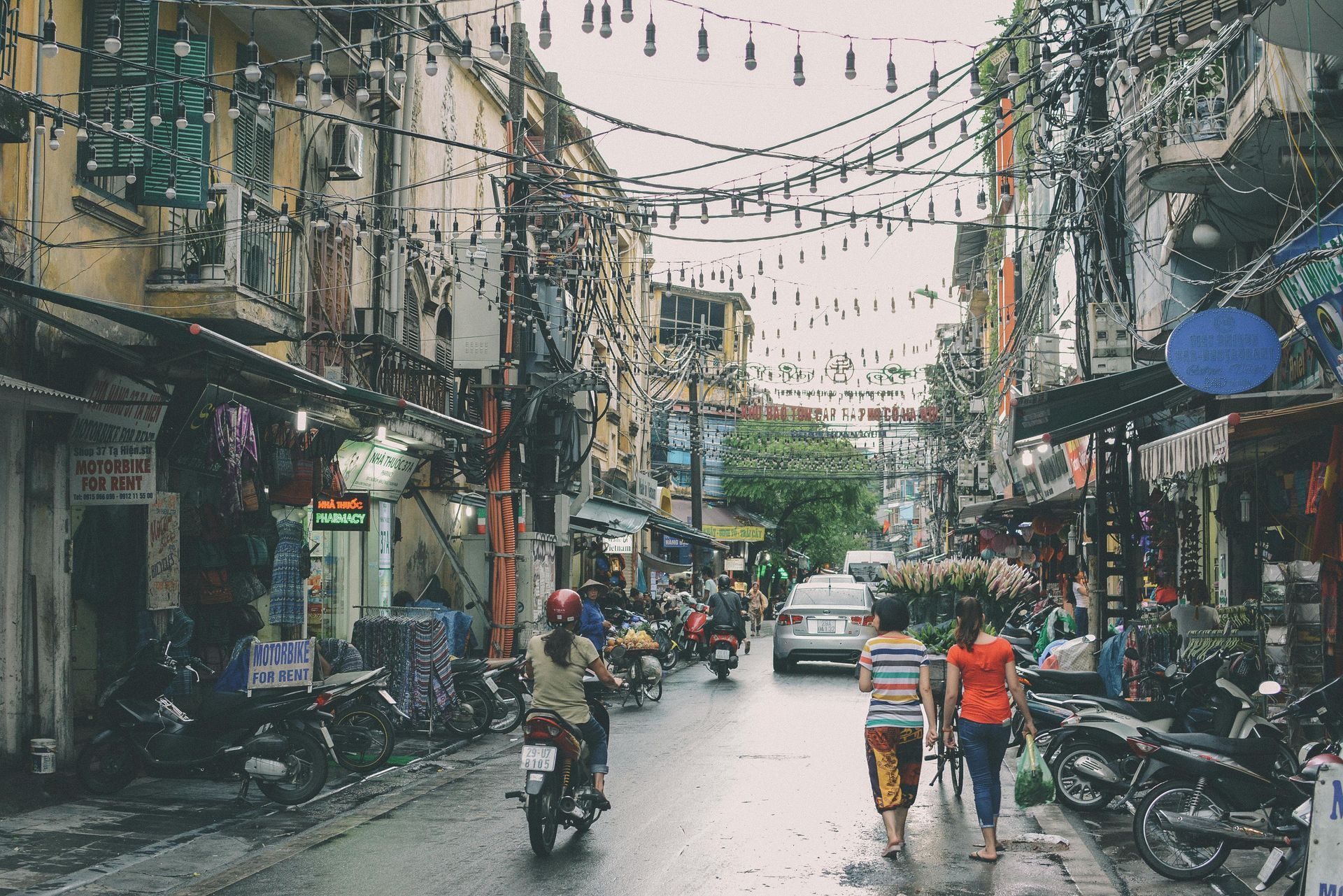 A couple of people walking down a busy street in Hanoi Old Quarter in Vietnam.