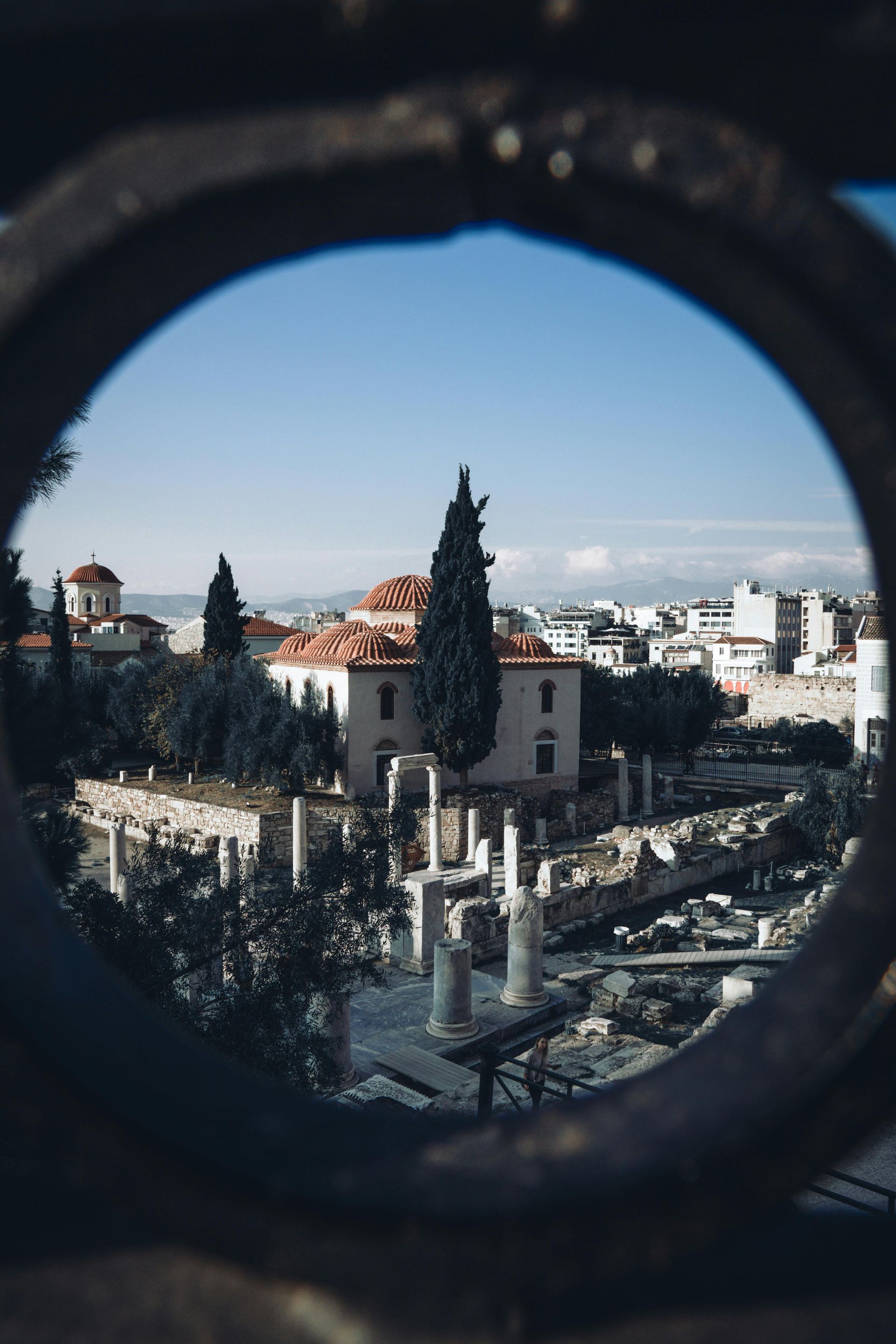 A view of a city through a hole in a fence in Athens, Greece.