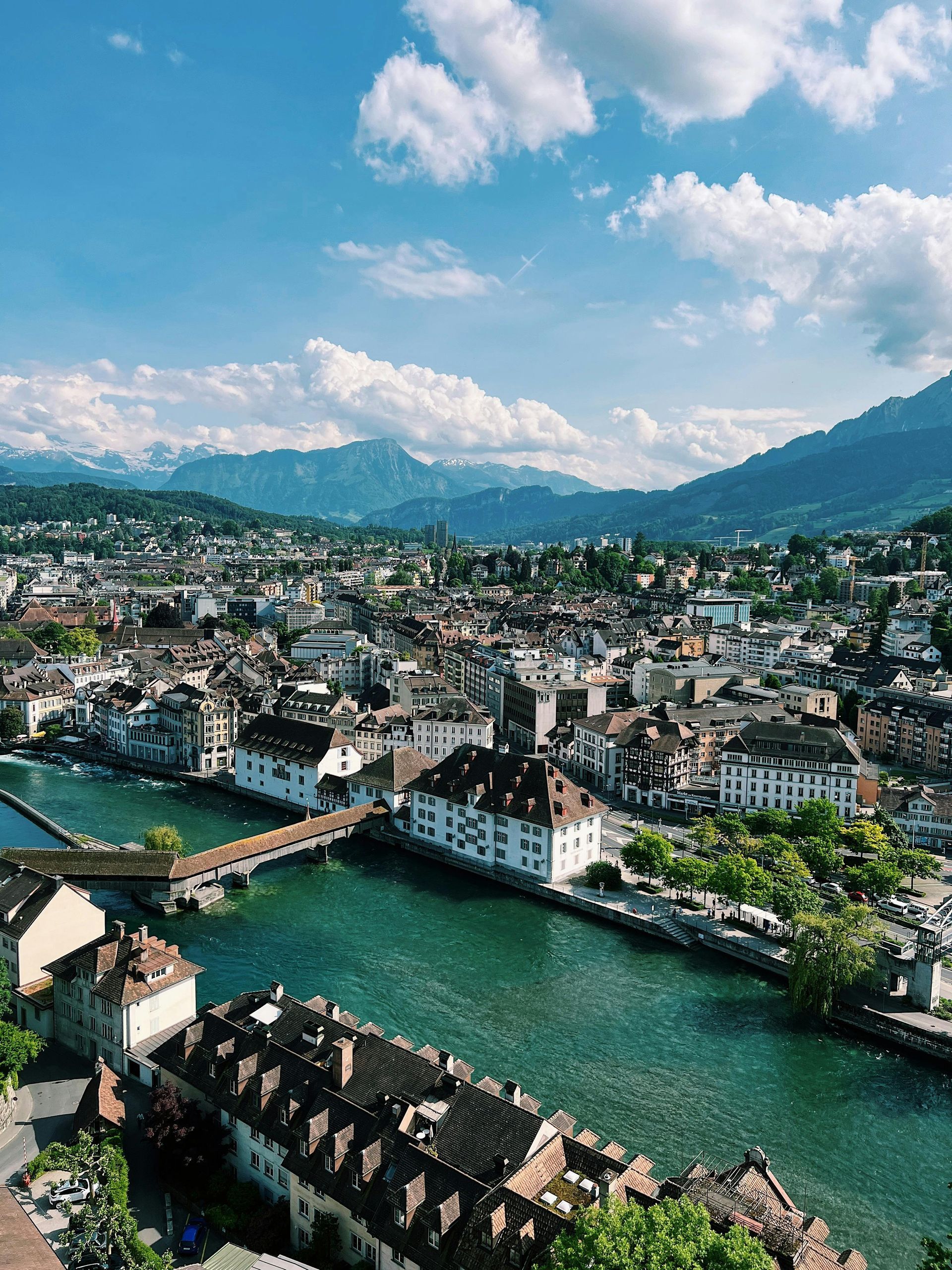 An aerial view of a city with a river running through it and mountains in the background in Switzerland.