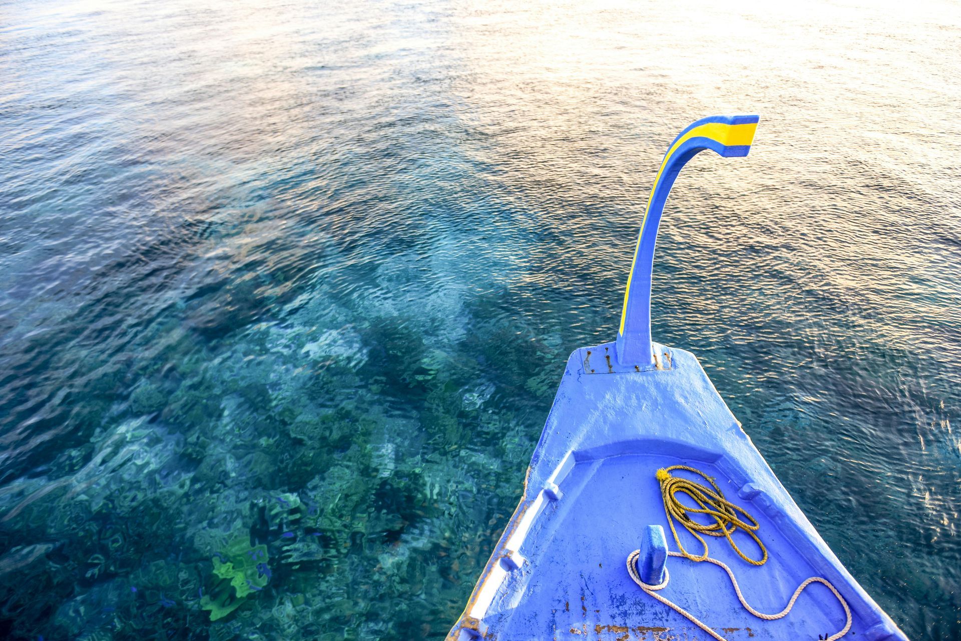 A blue boat is floating on top of a body of water in the Caribbean.