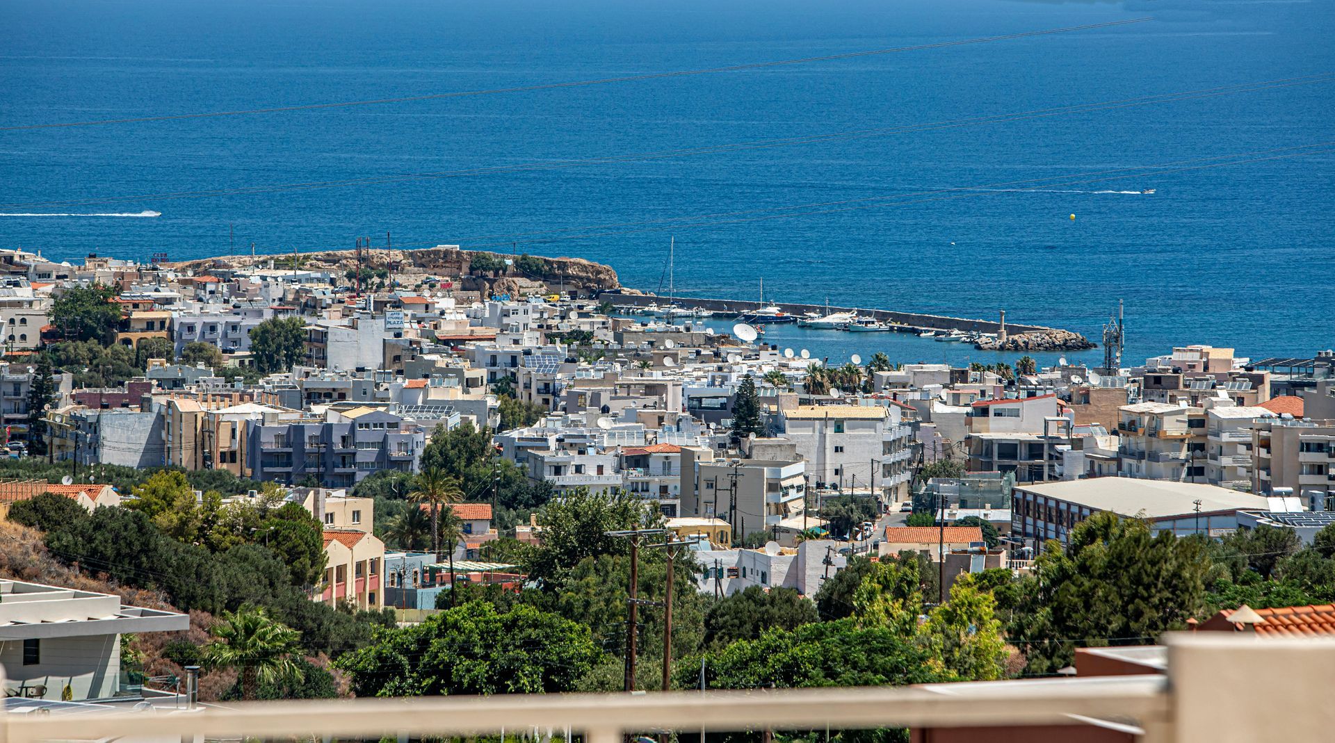 A view of a city from a balcony overlooking the ocean in Crete, Greece.