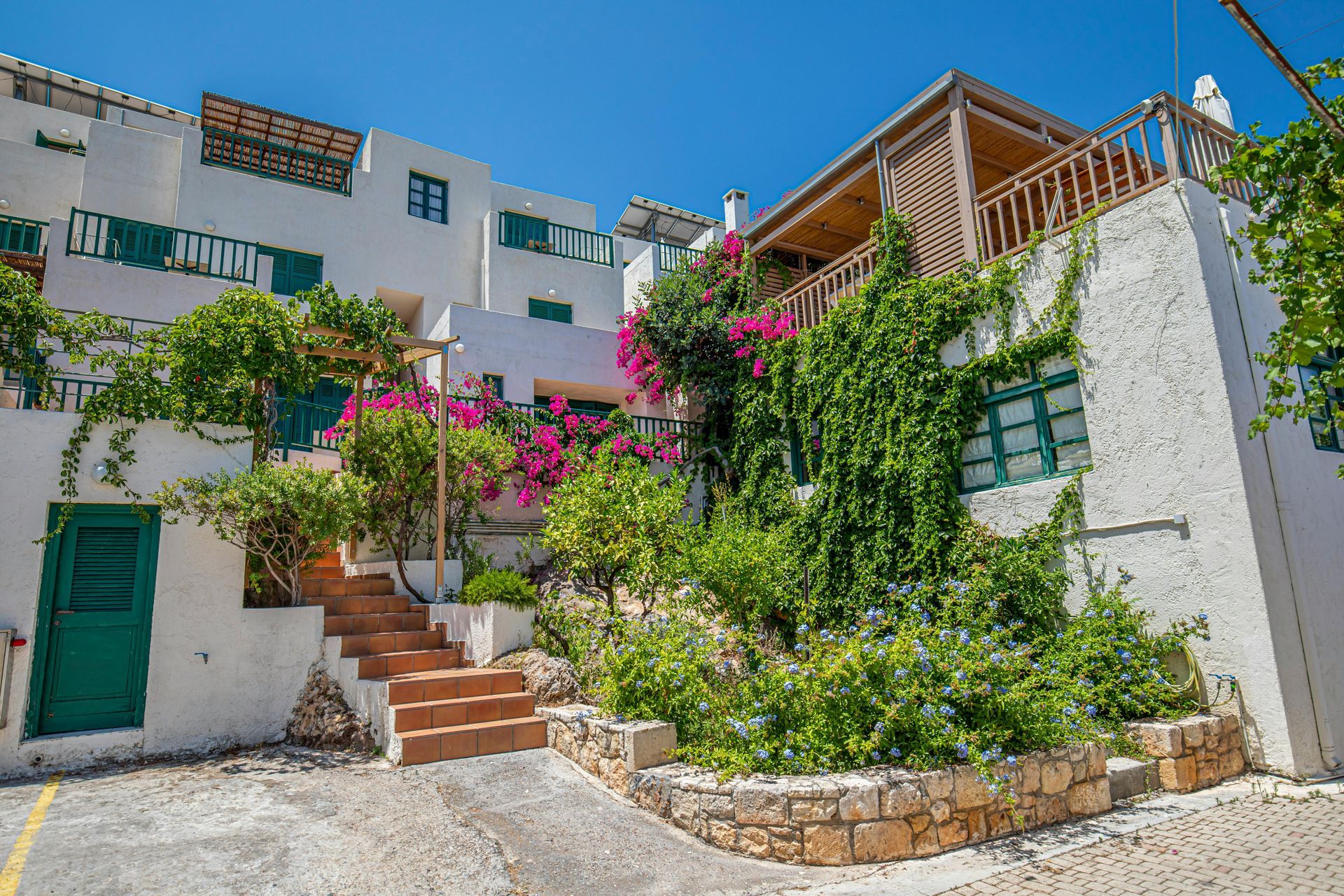 A white building with a green door and stairs in front of it in Crete, Greece.