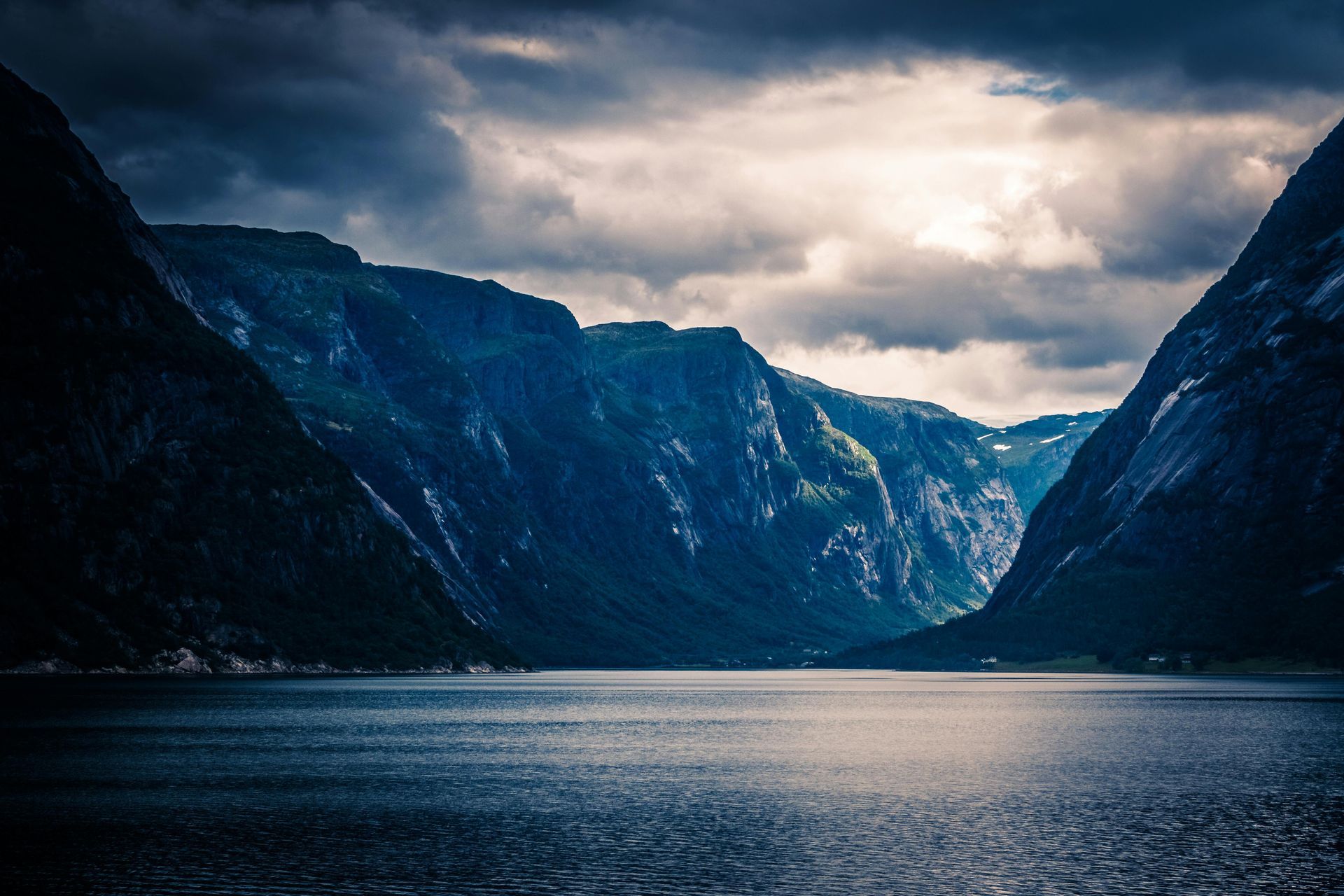 A large body of water surrounded by mountains on a cloudy day in Norway.