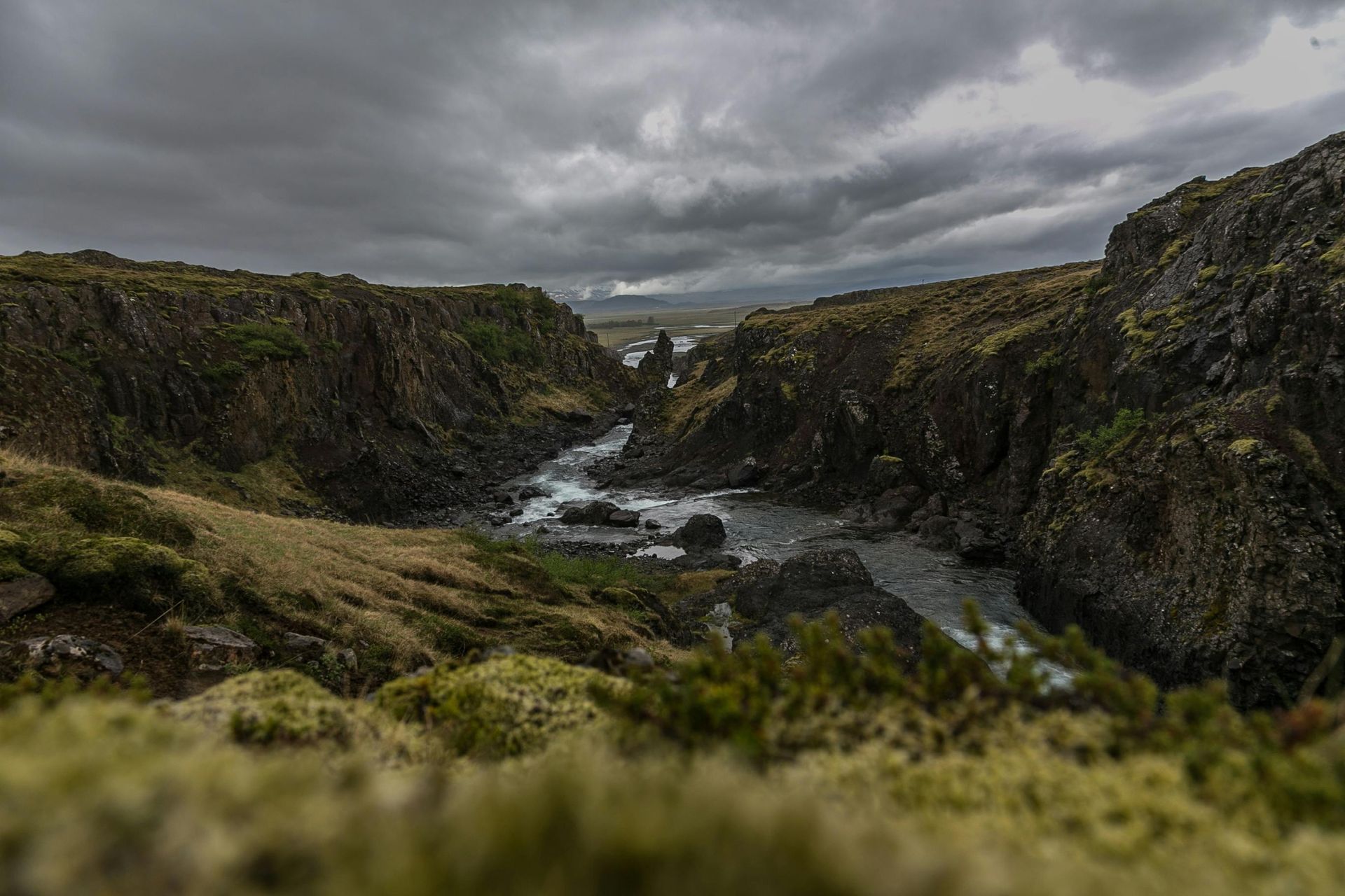 A river flowing through a canyon surrounded by rocks on a cloudy day in Iceland.