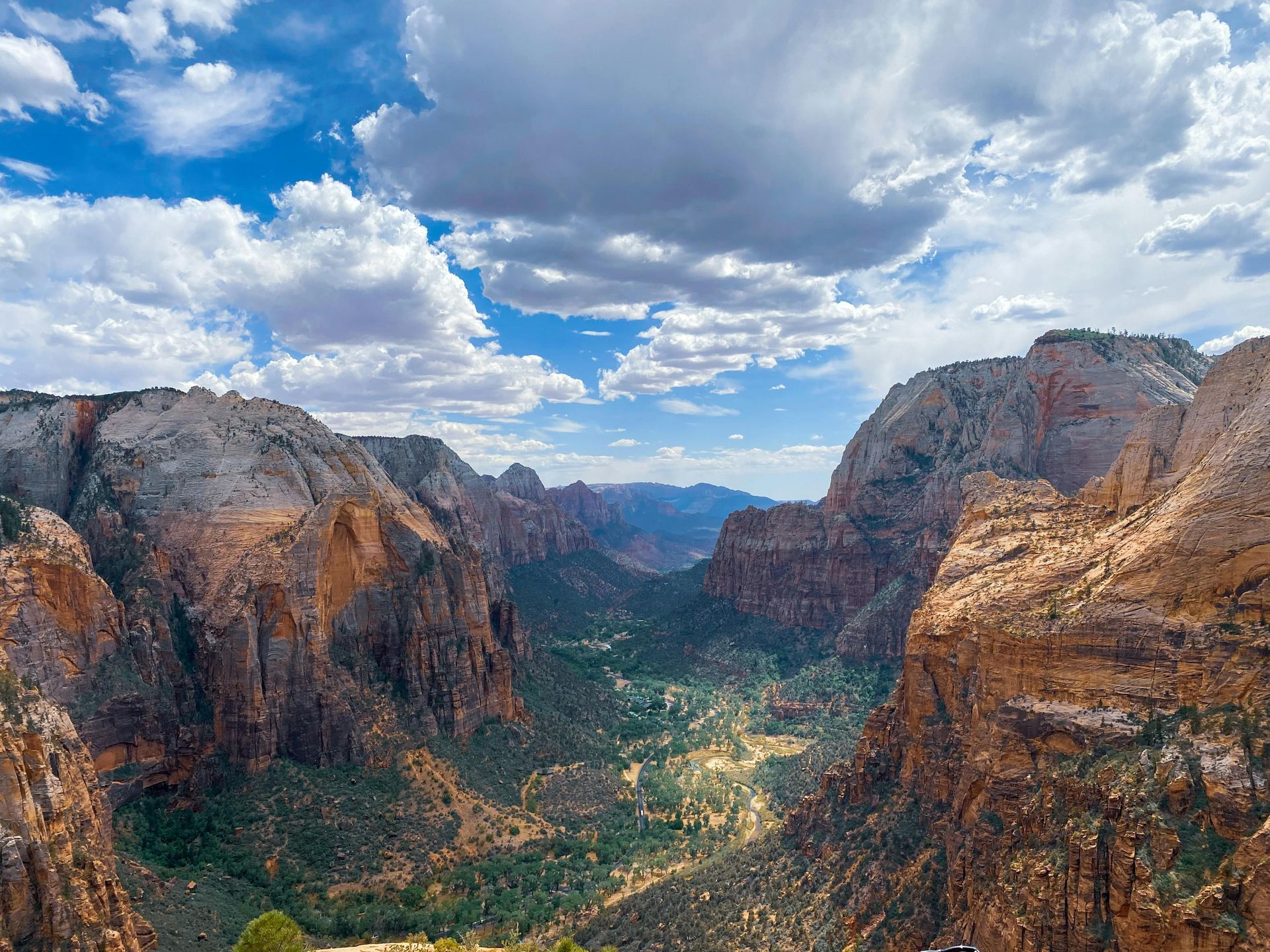 An aerial view of a canyon with mountains in the background and clouds in the sky at Angels Landing in Utah.