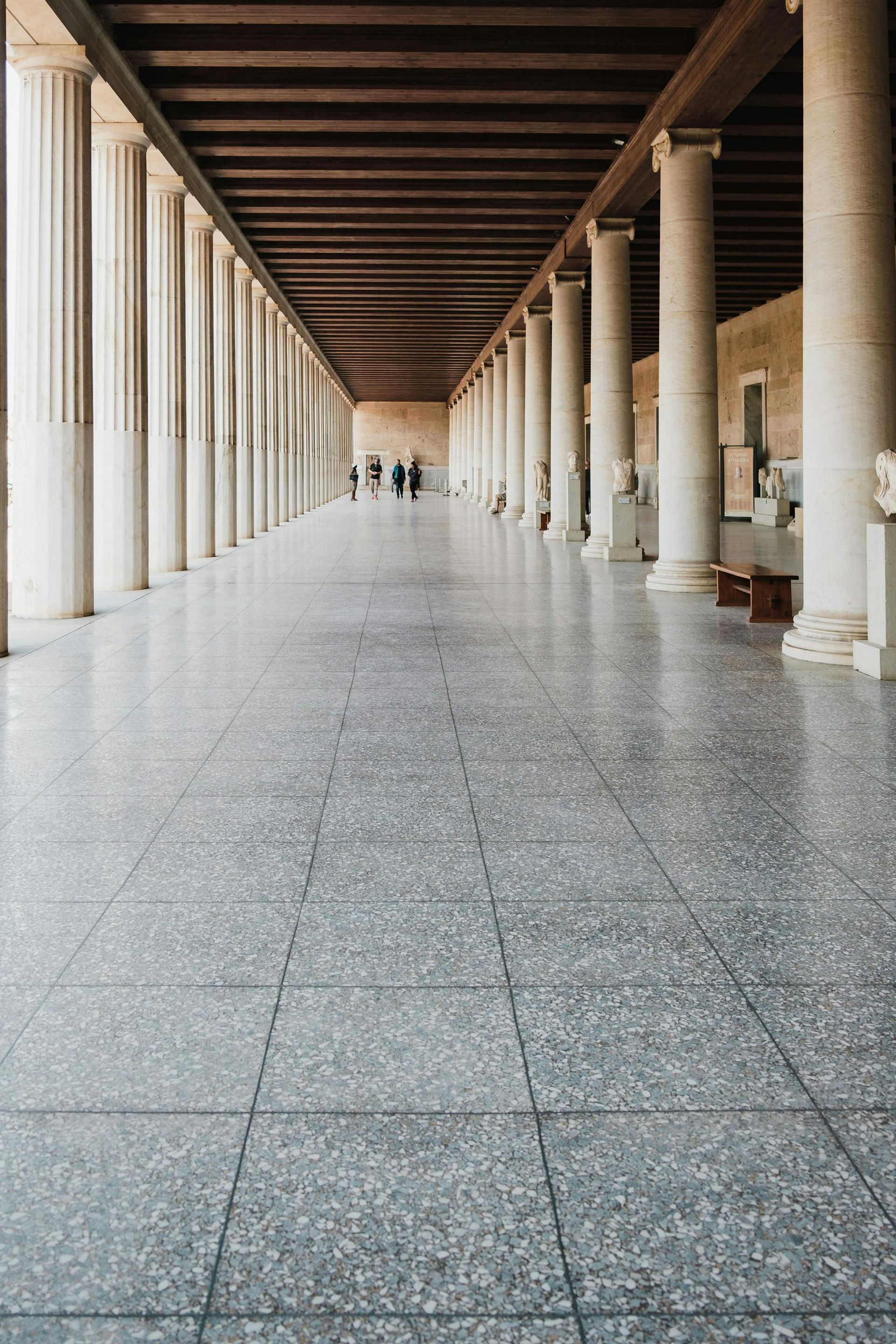 A long hallway with columns and a tiled floor in a building in Athens, Greece.